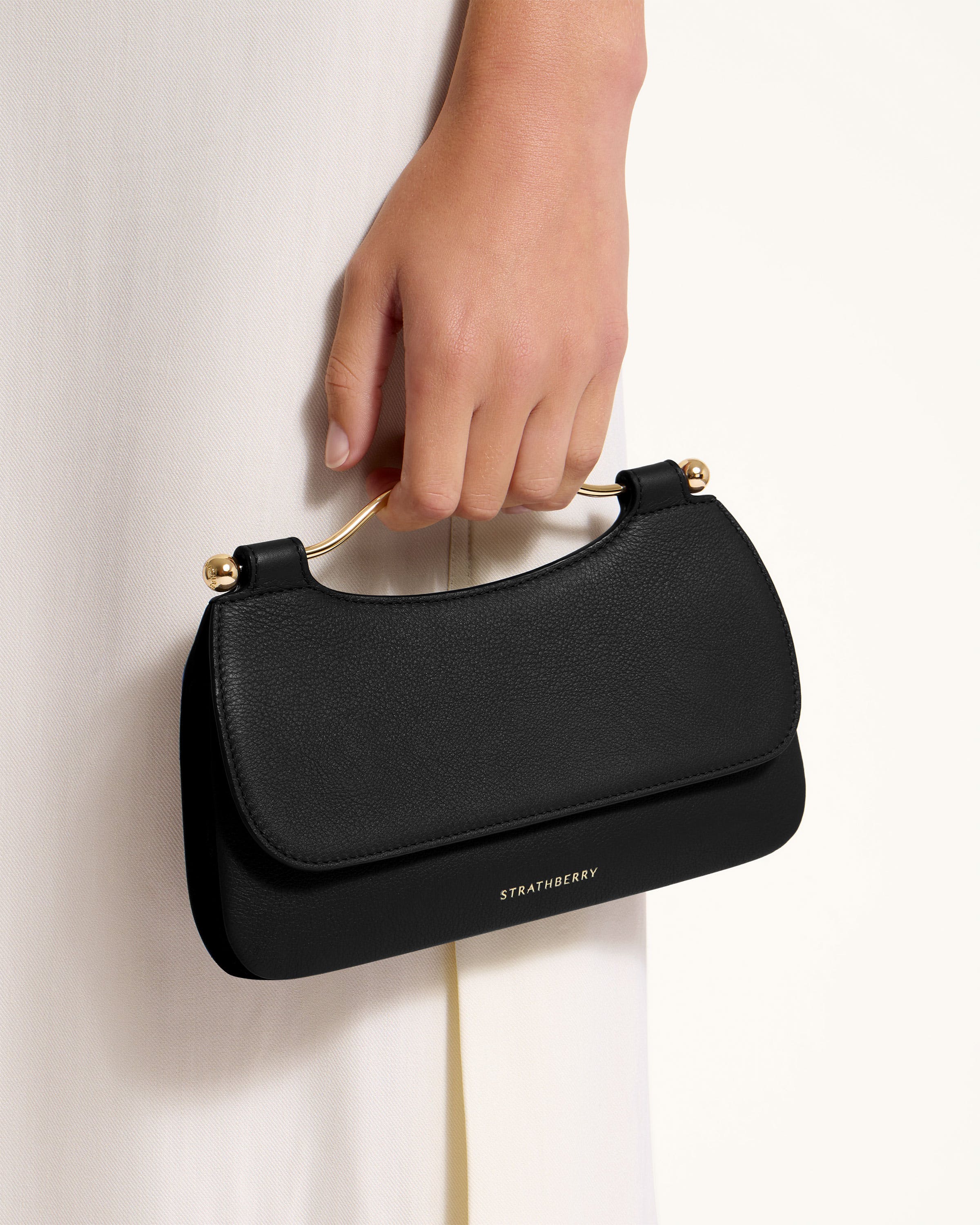 A woman's hand holding a black purse