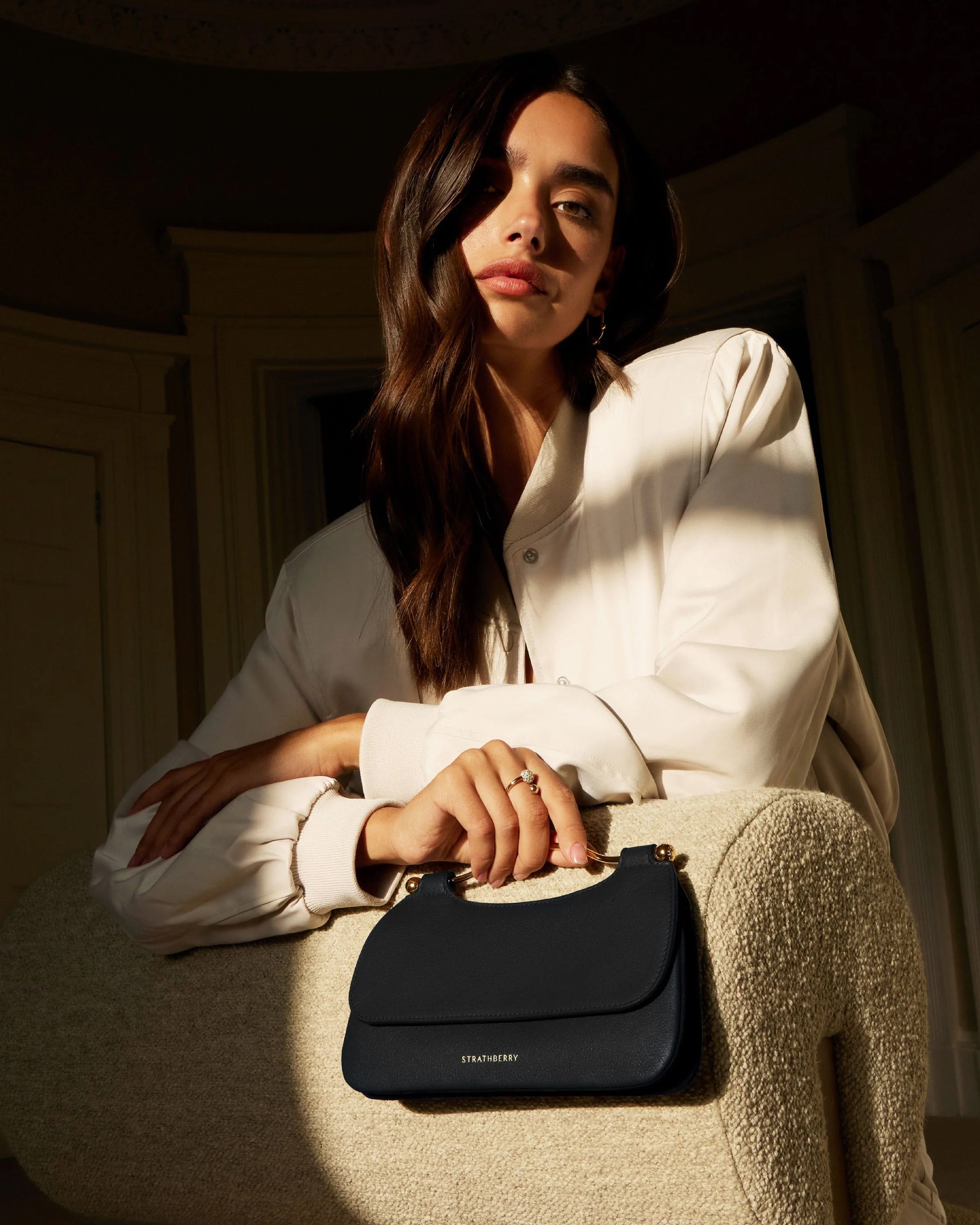 A woman sitting on a chair holding a black purse