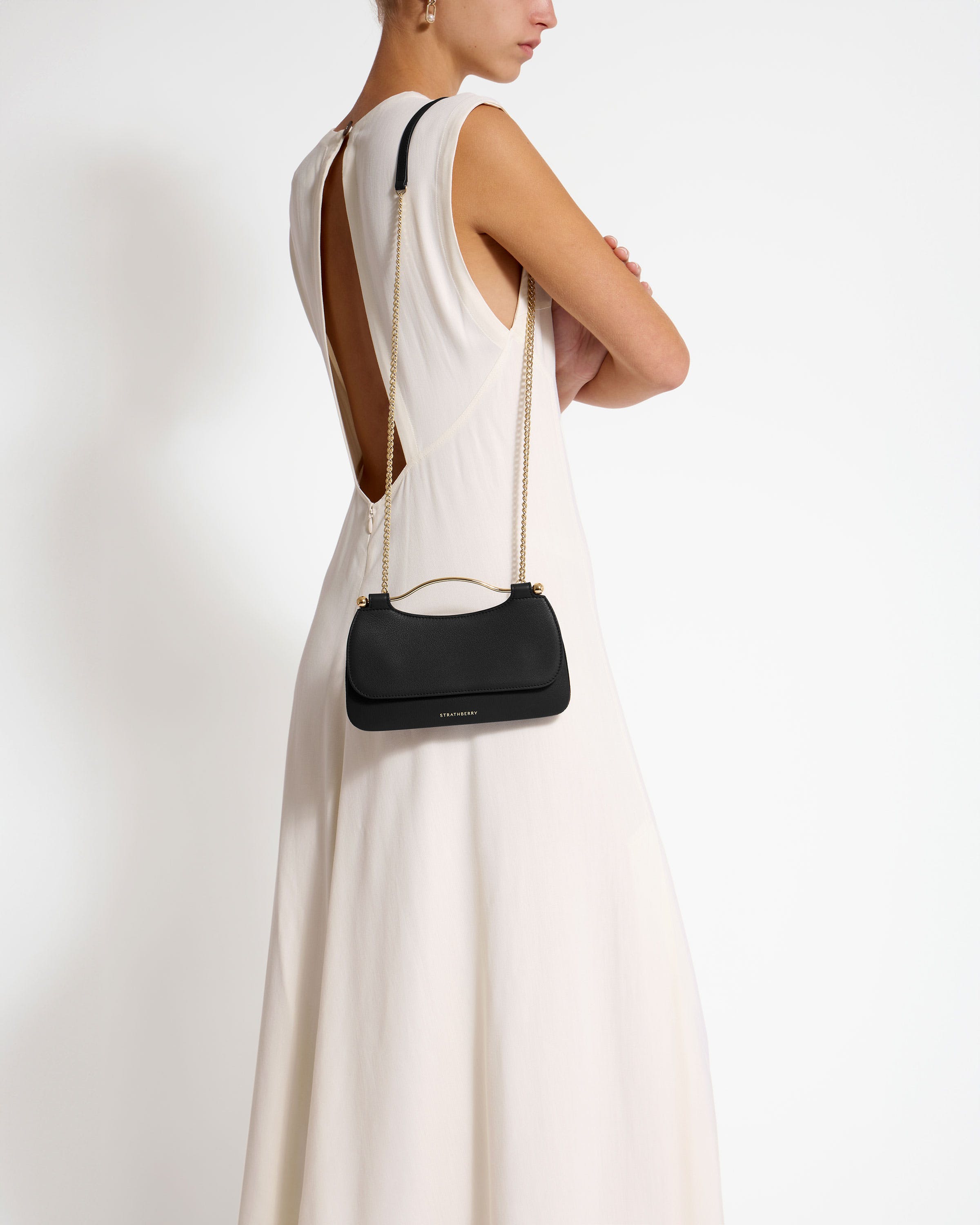 A woman in a white dress holding a black purse