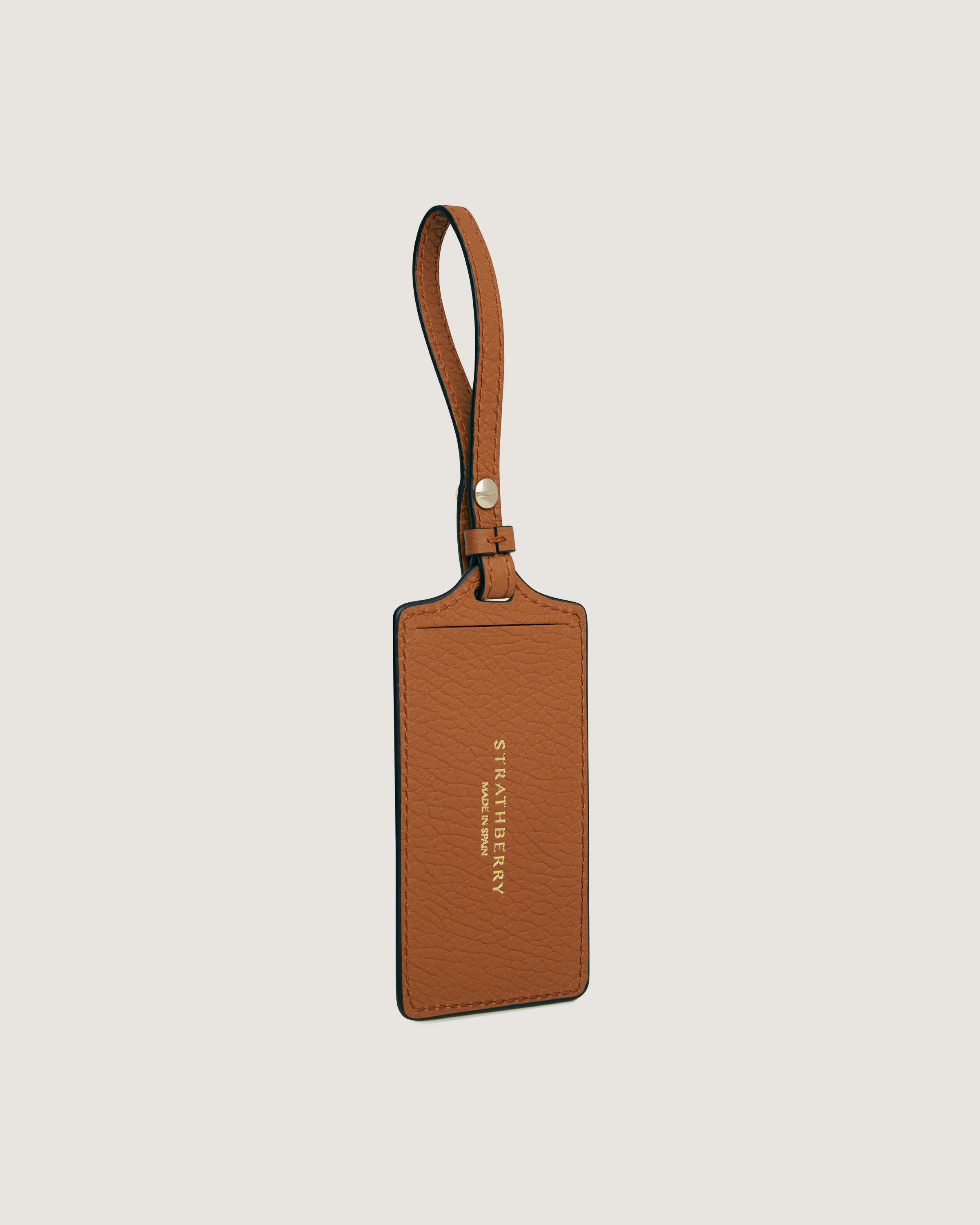 A tan leather luggage tag hanging from a leather strap