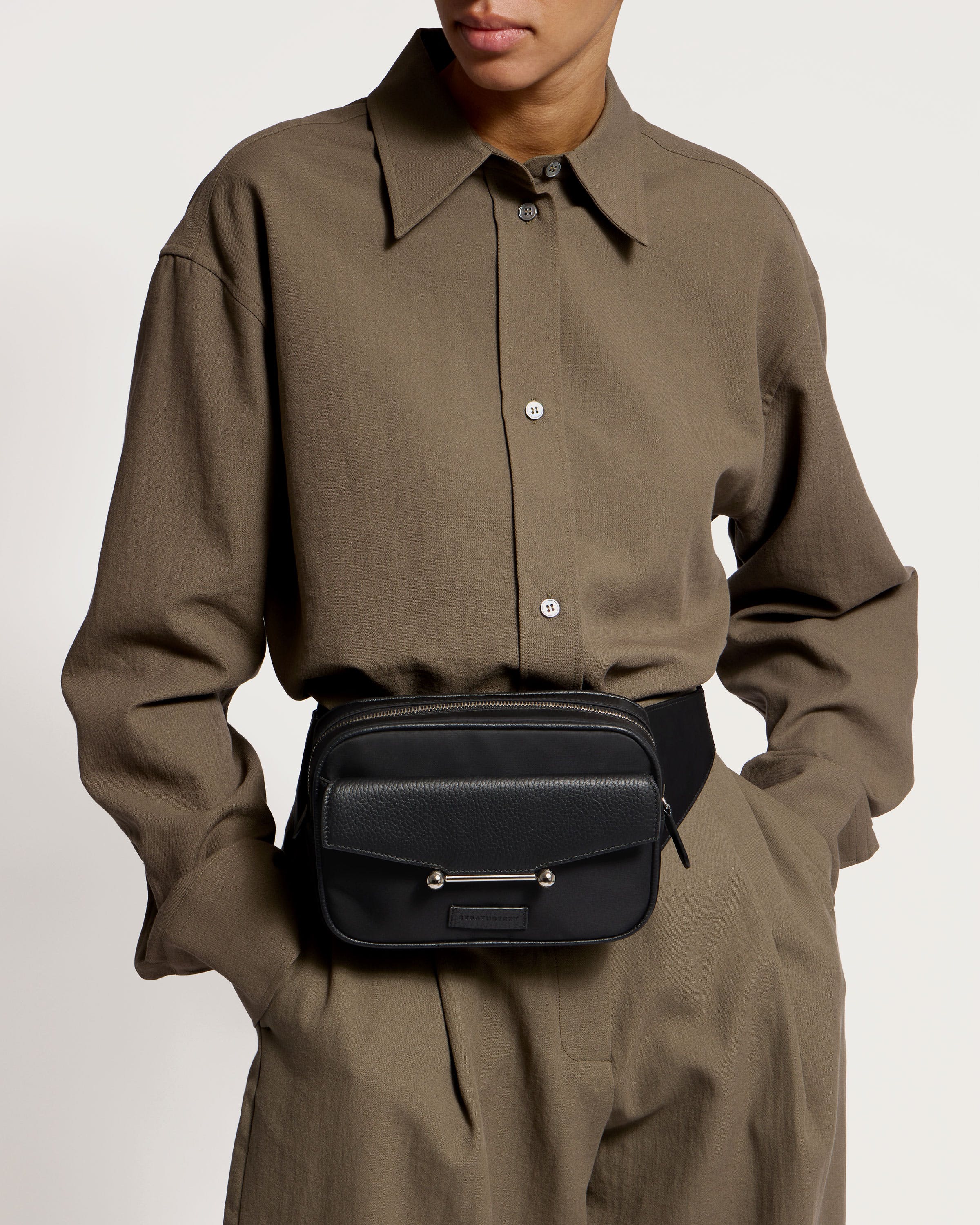 A man wearing a brown shirt and a black belt bag