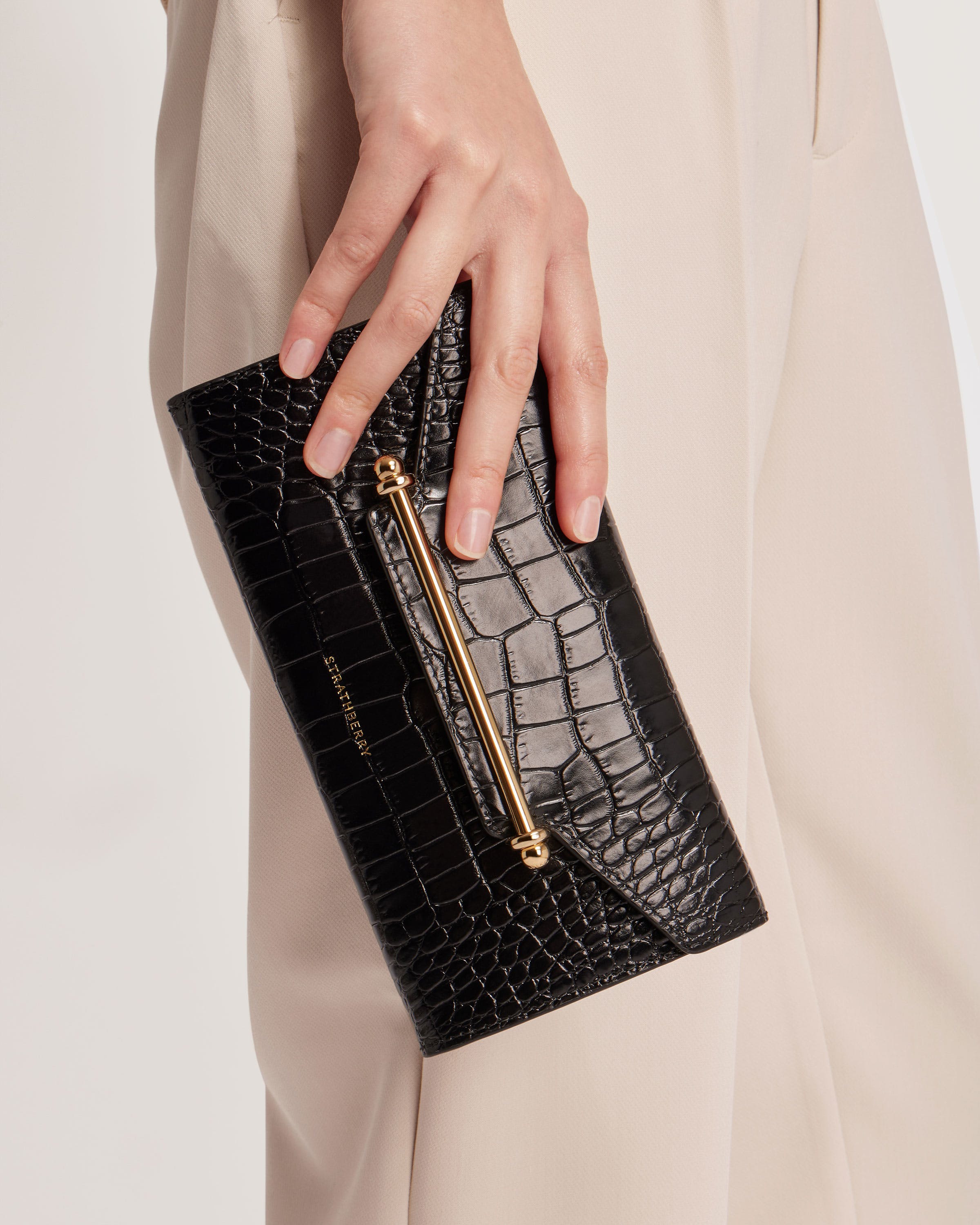 A woman's hand holding a black purse