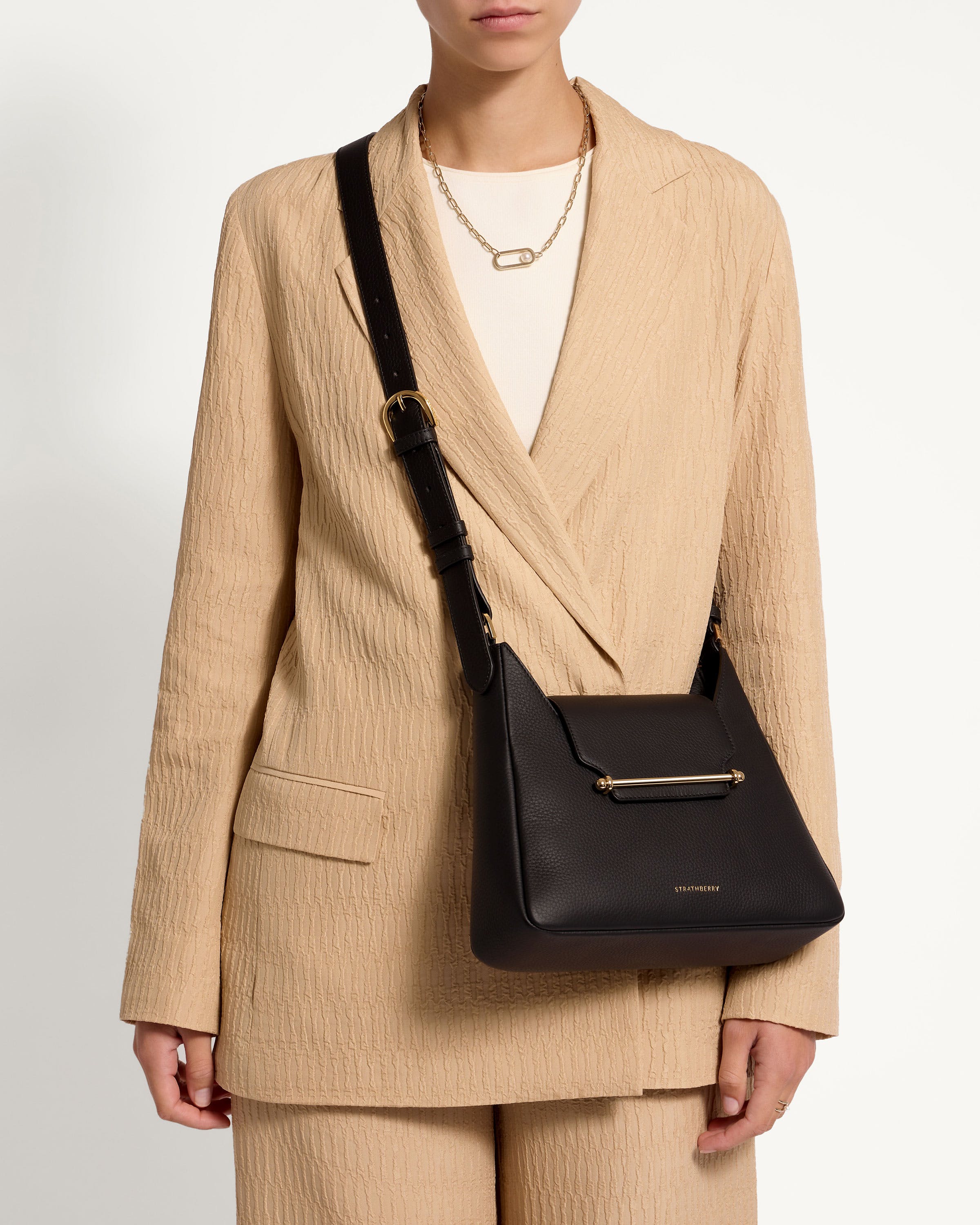 A woman wearing a beige suit and a black bag