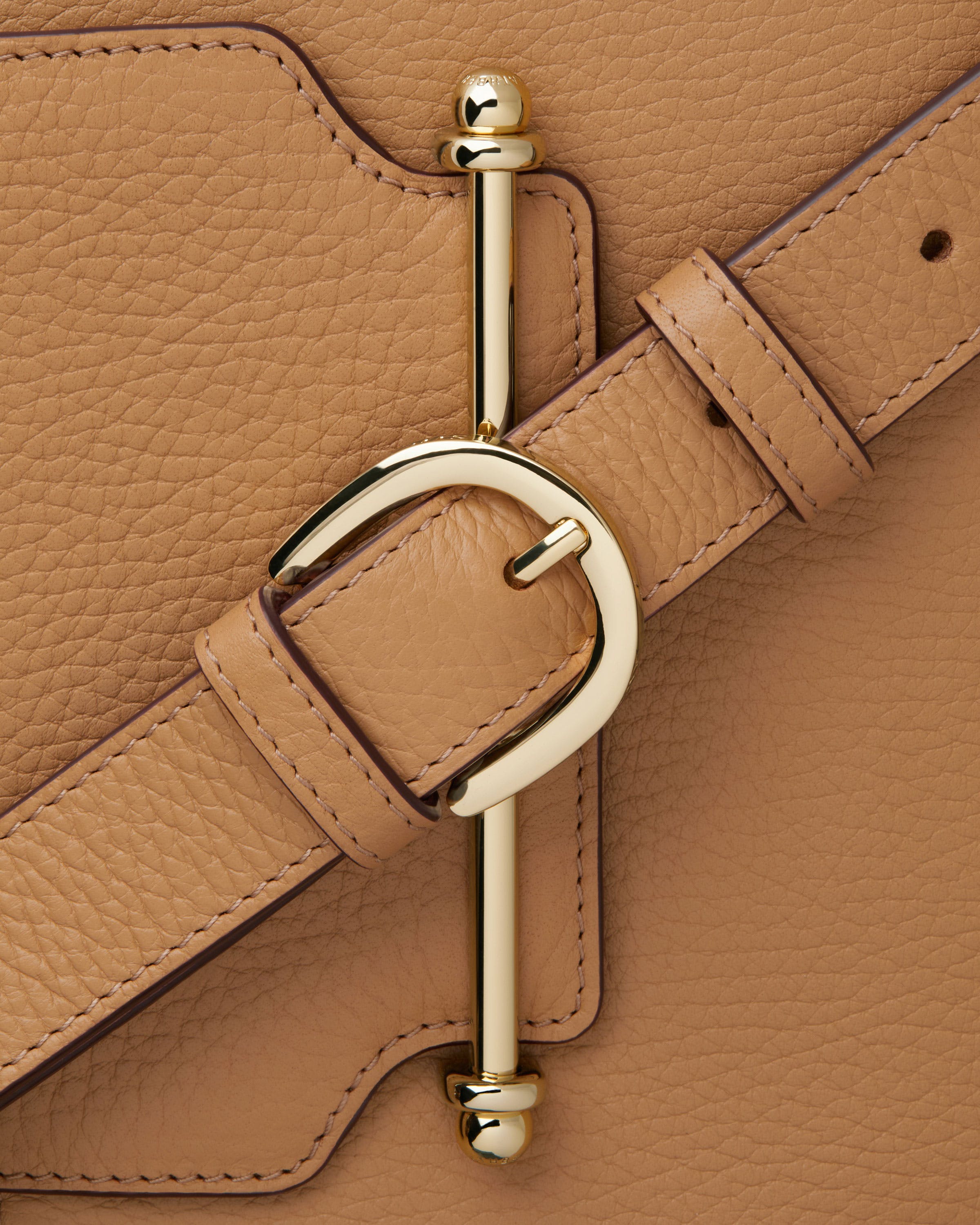 A close up of a tan purse with a metal handle