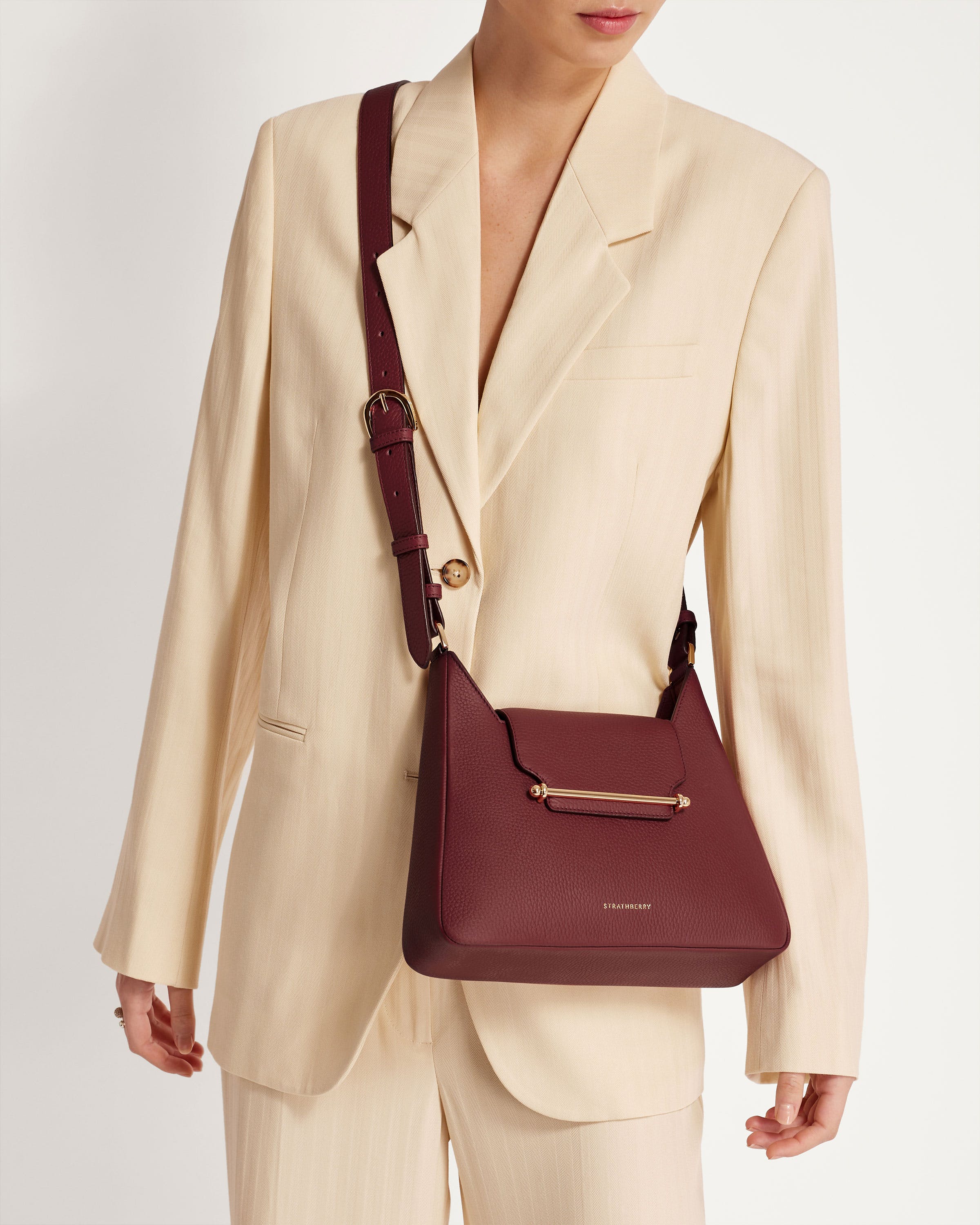 A woman wearing a white suit and a maroon purse