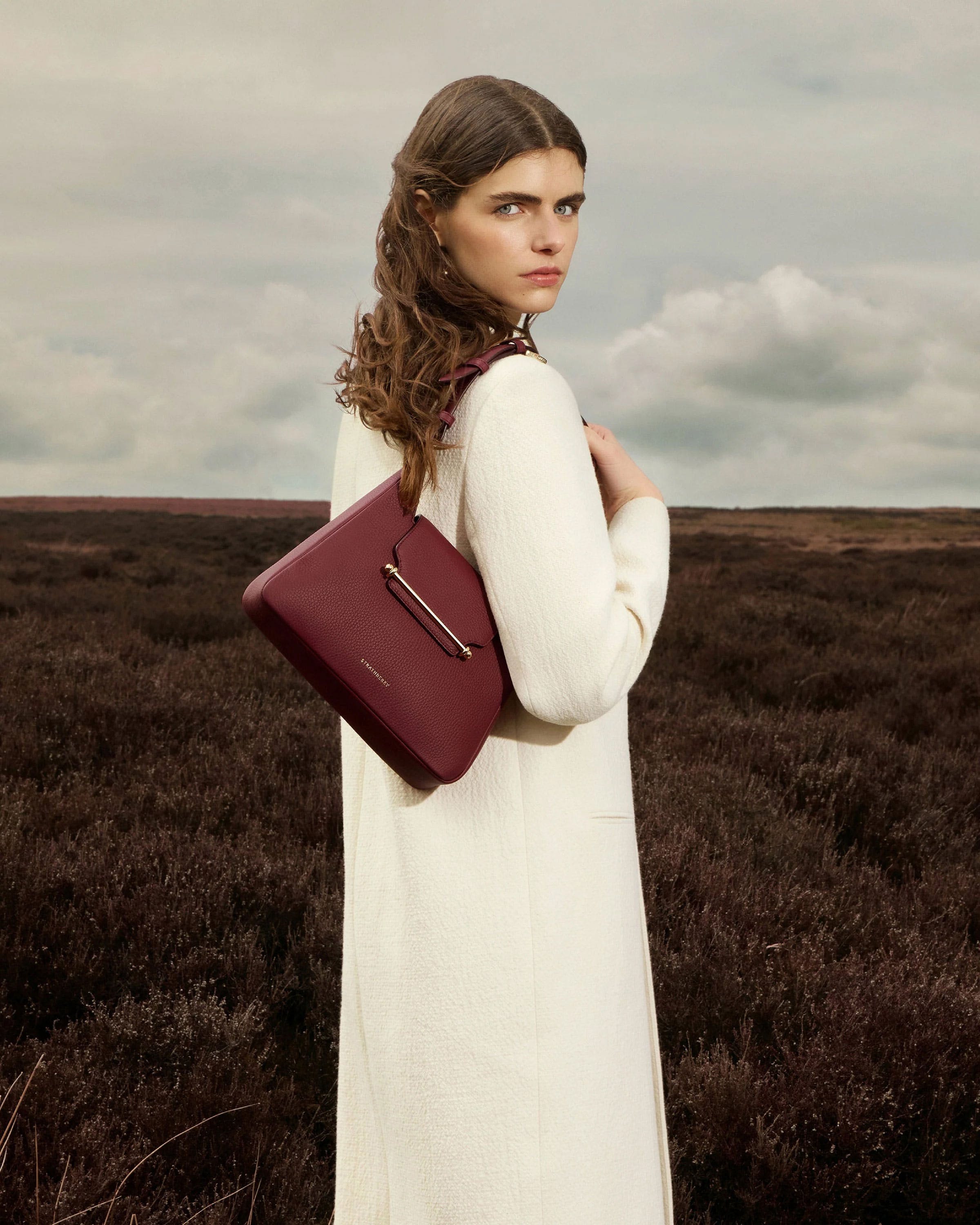 A woman in a white dress holding a red purse