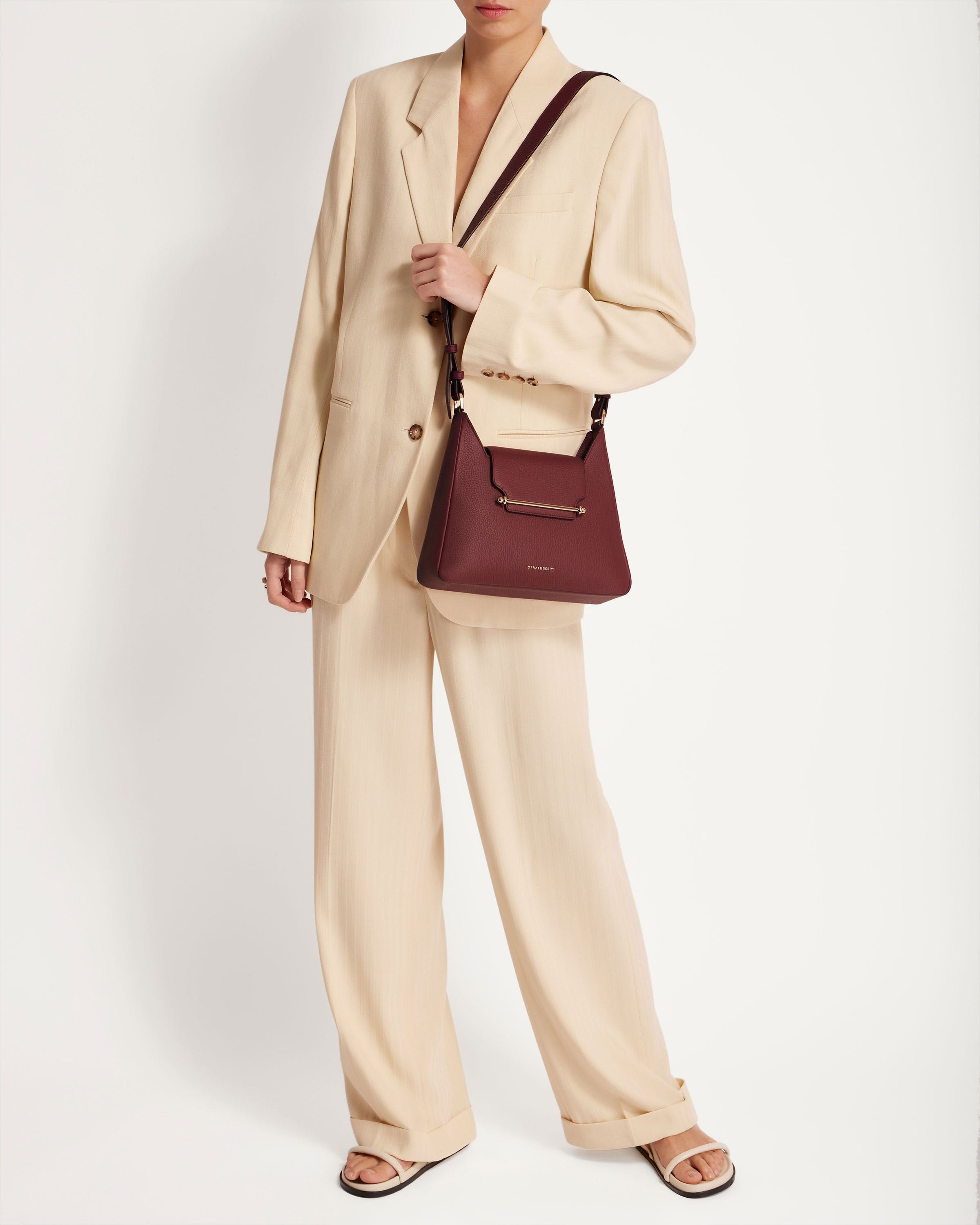 A woman in a beige suit holding a brown purse