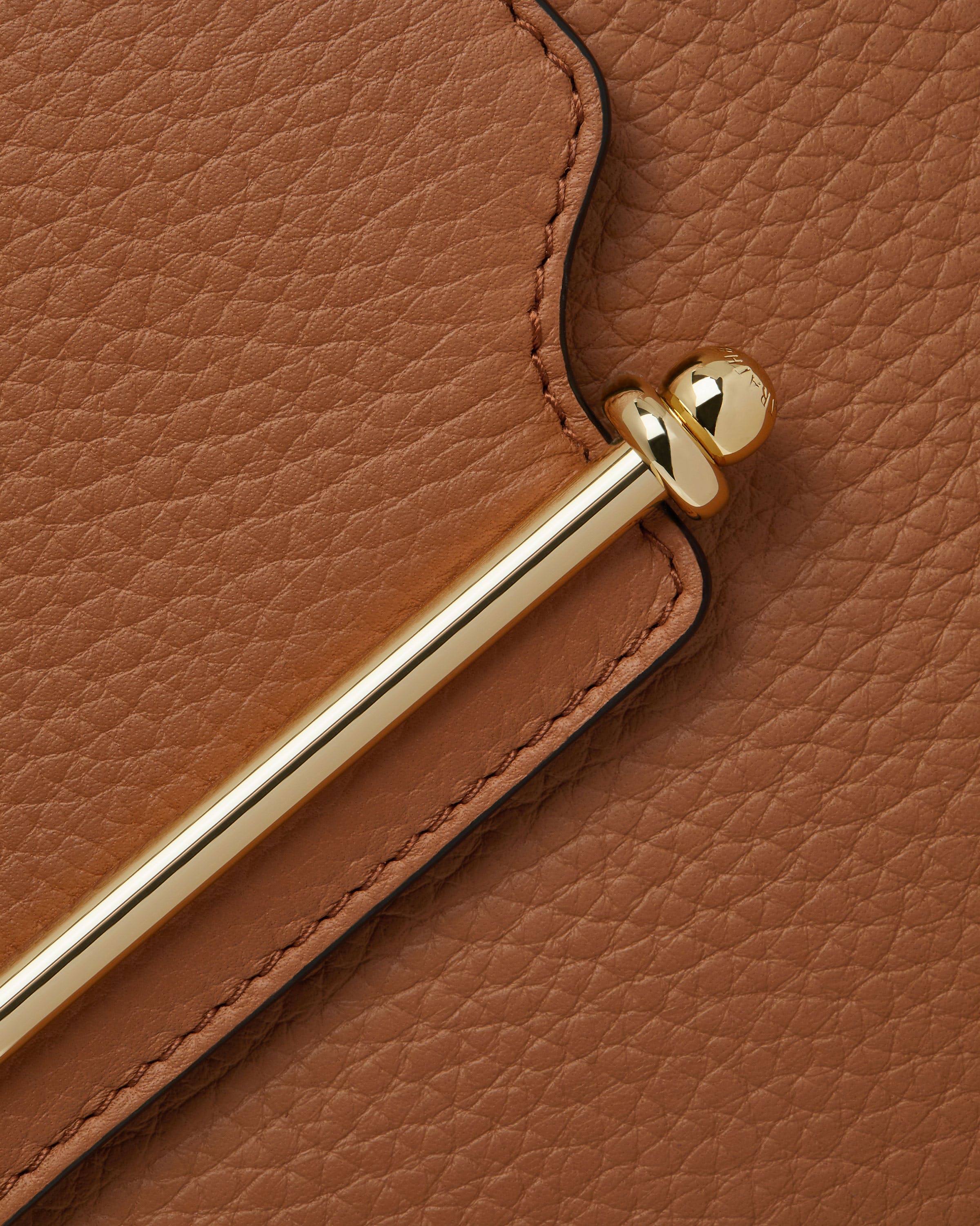 A close up of a brown purse with a gold handle