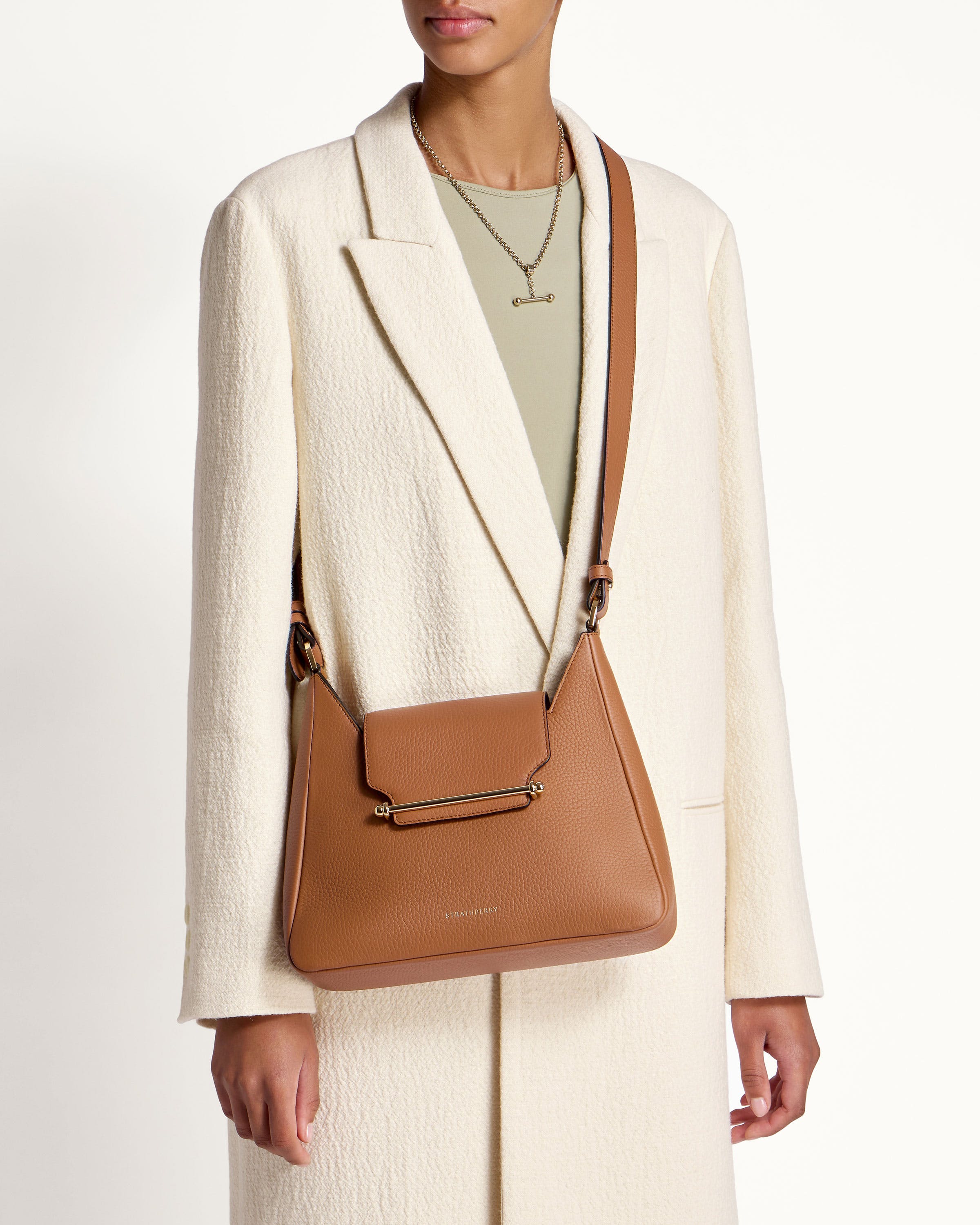 A woman in a white coat holding a brown purse