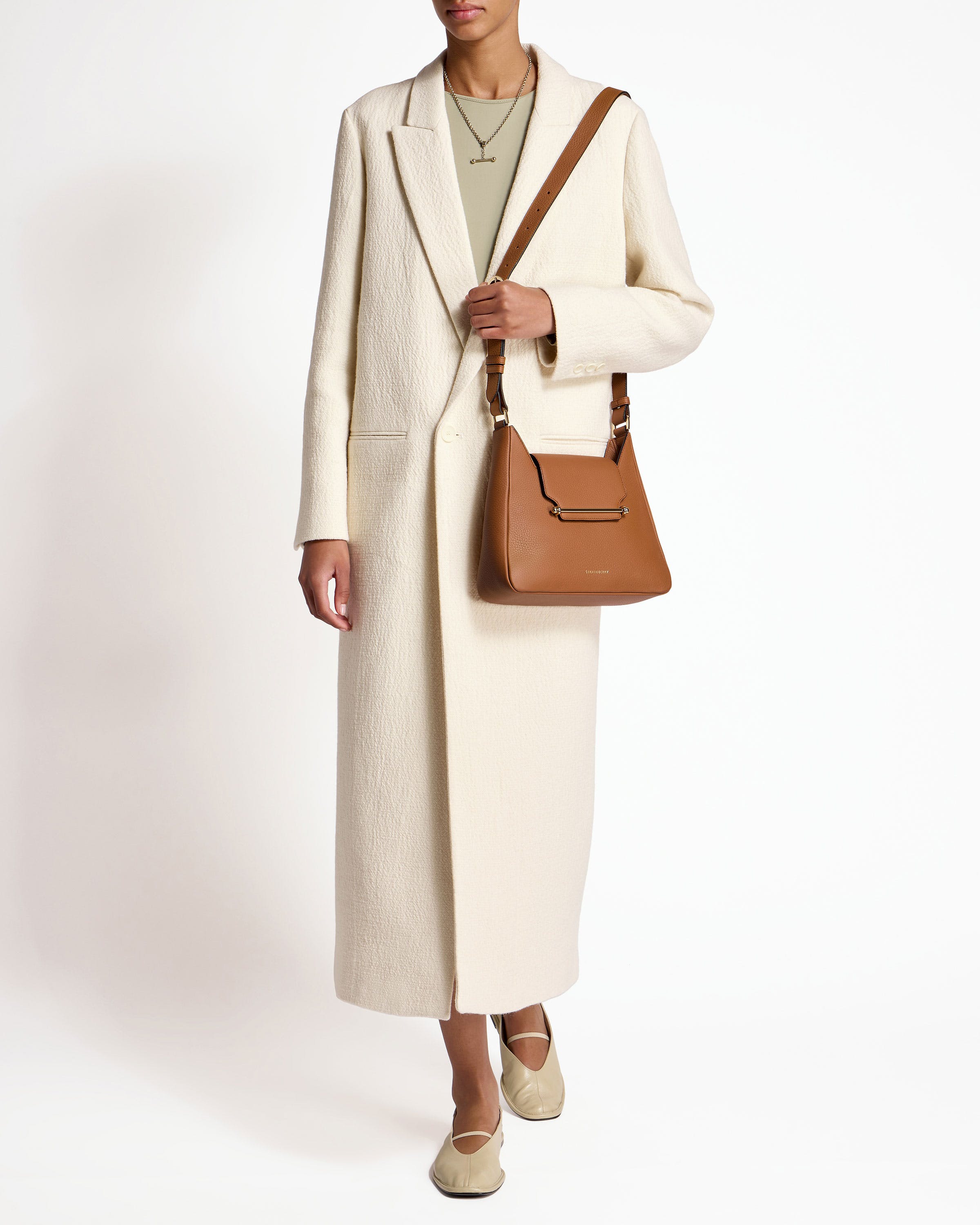 A woman in a white coat holding a brown purse