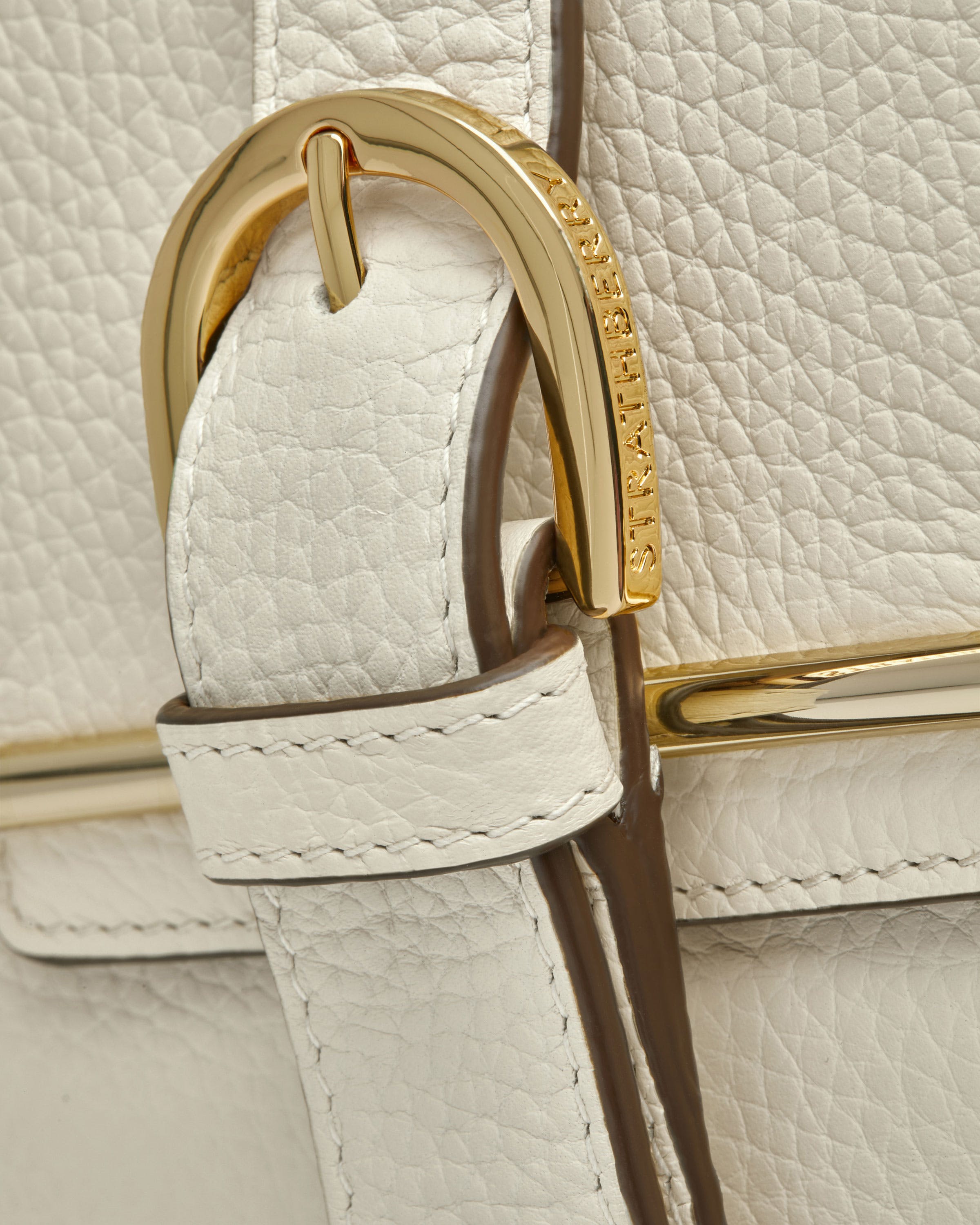 A close up of a white and gold purse