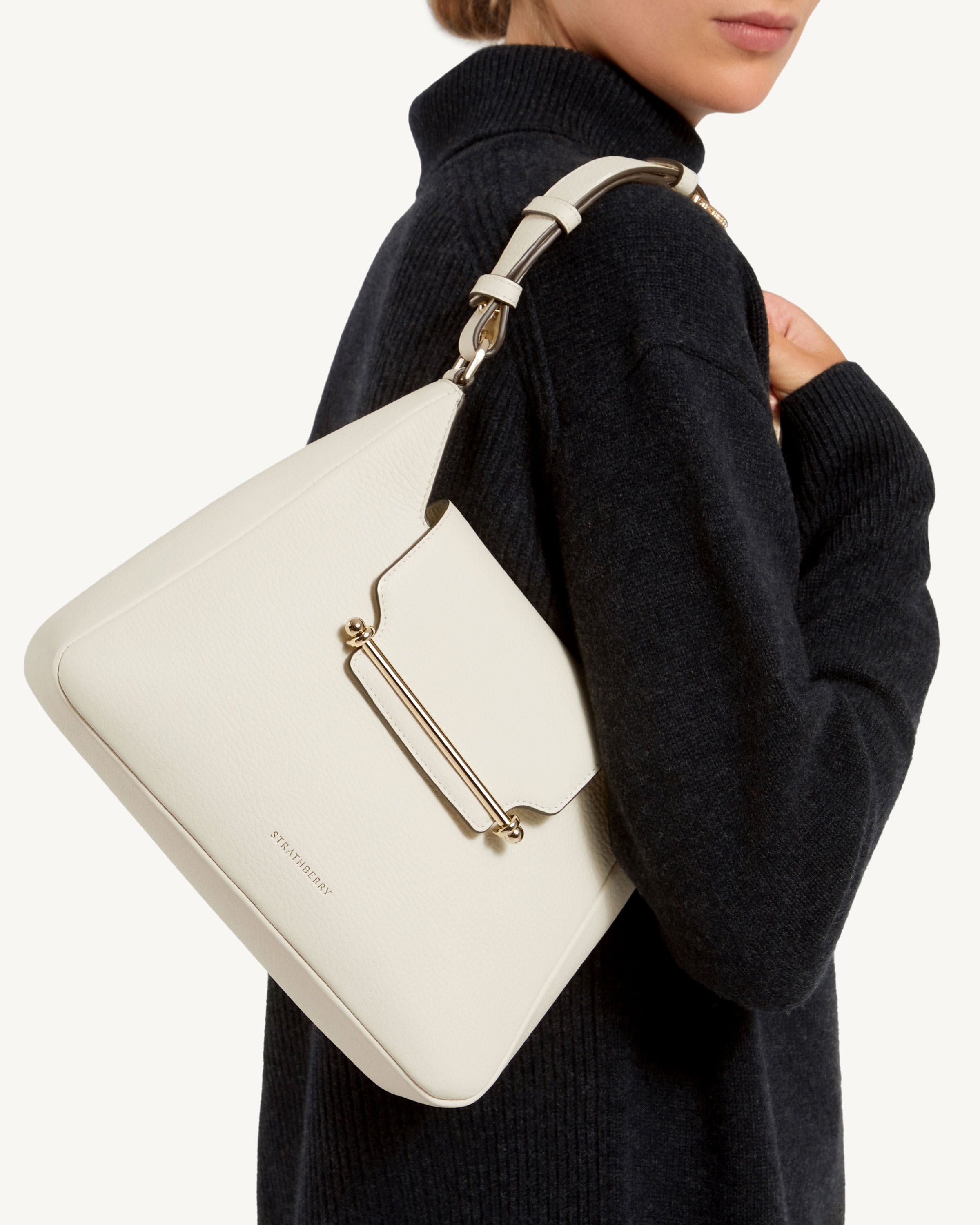 A woman in a black sweater holding a white purse