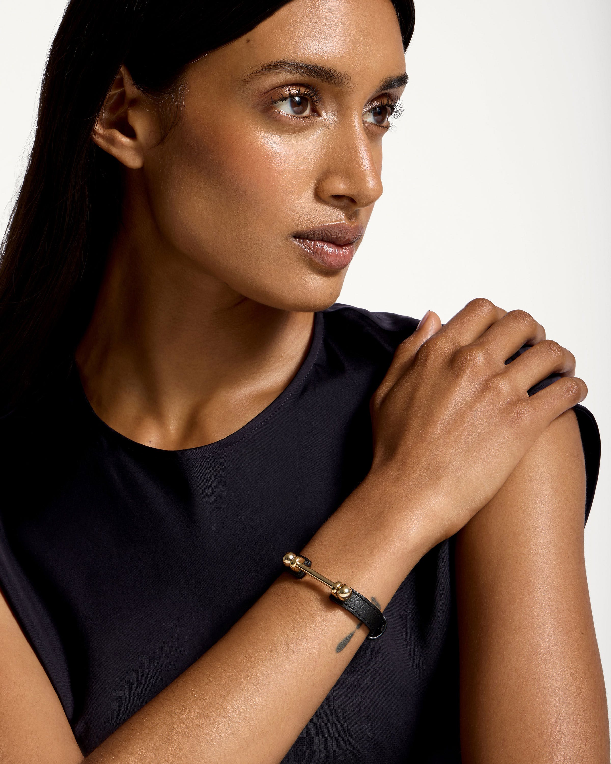 A woman wearing a black shirt and a gold bracelet