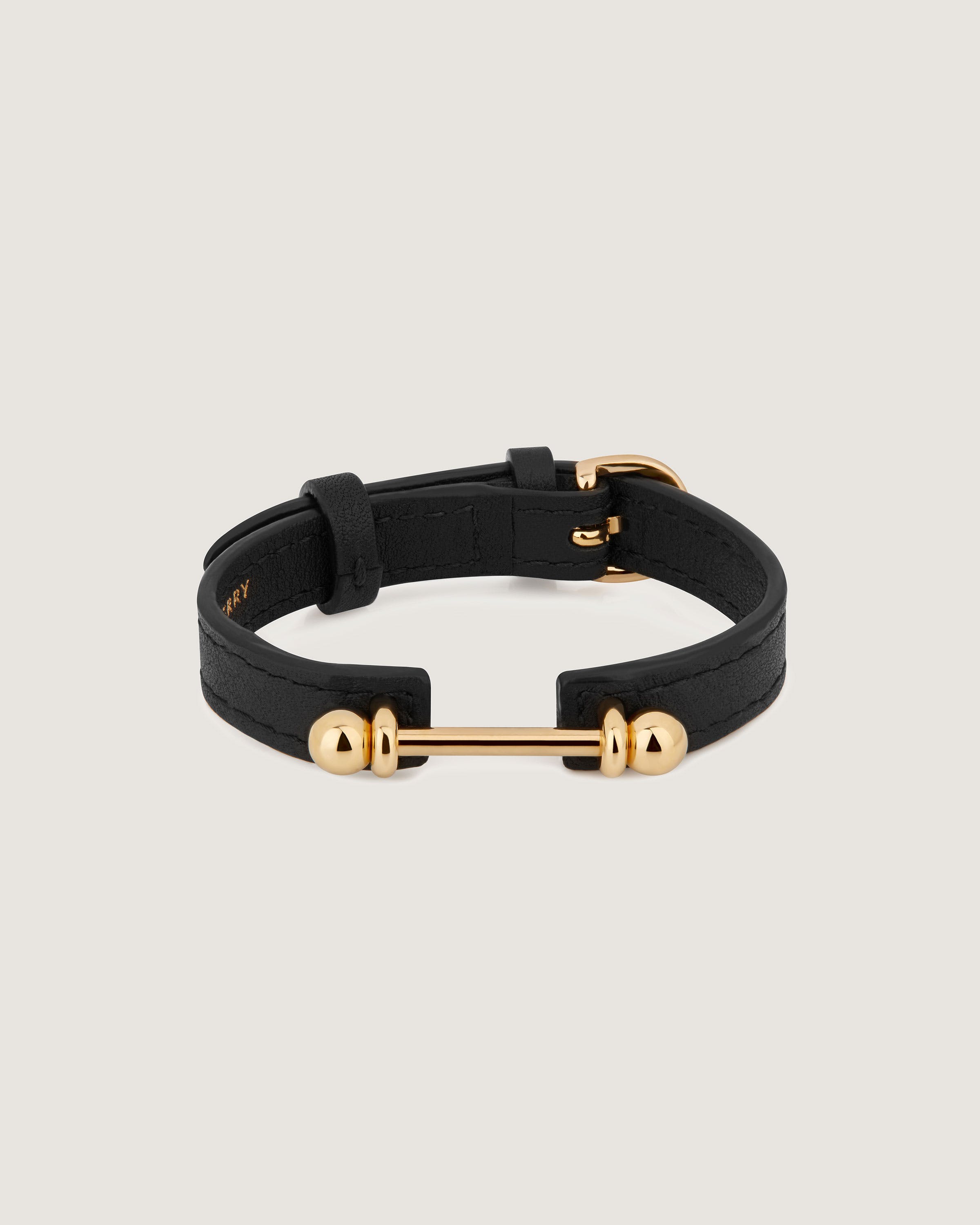 A black leather bracelet with two gold balls