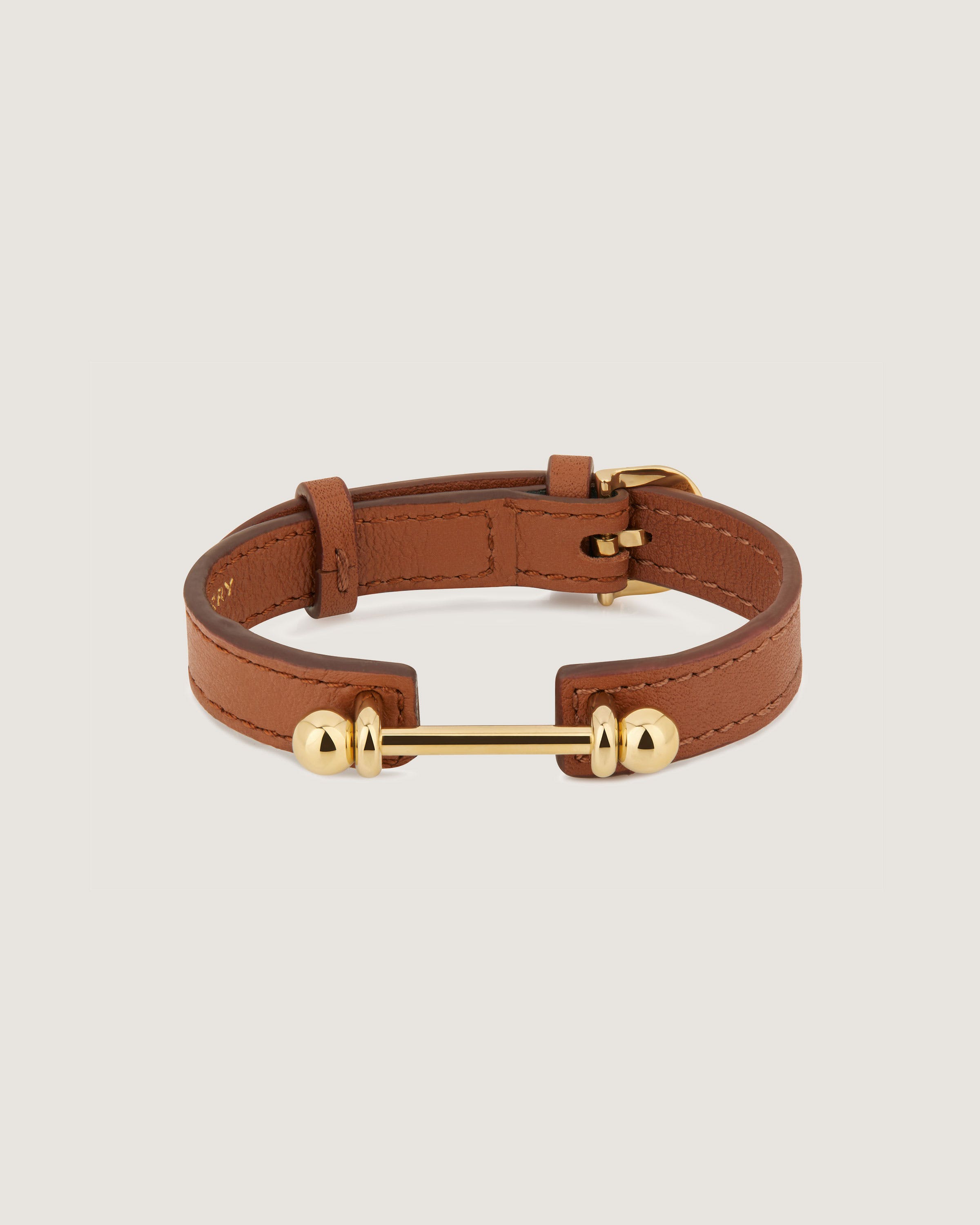 A brown leather bracelet with a gold clasp