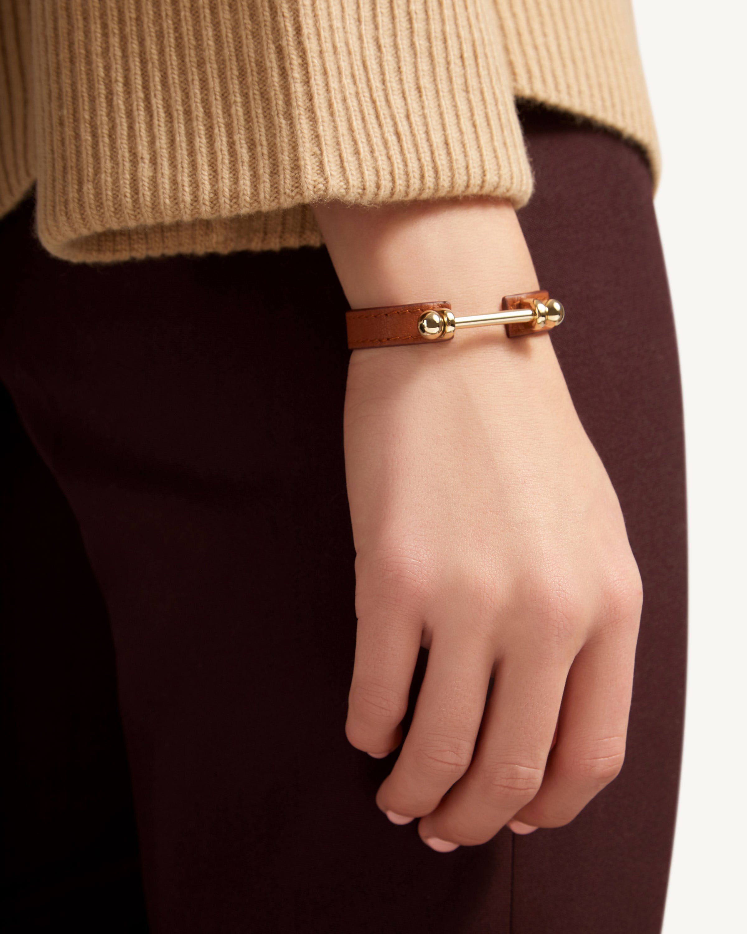 A woman wearing a brown bracelet and a brown sweater