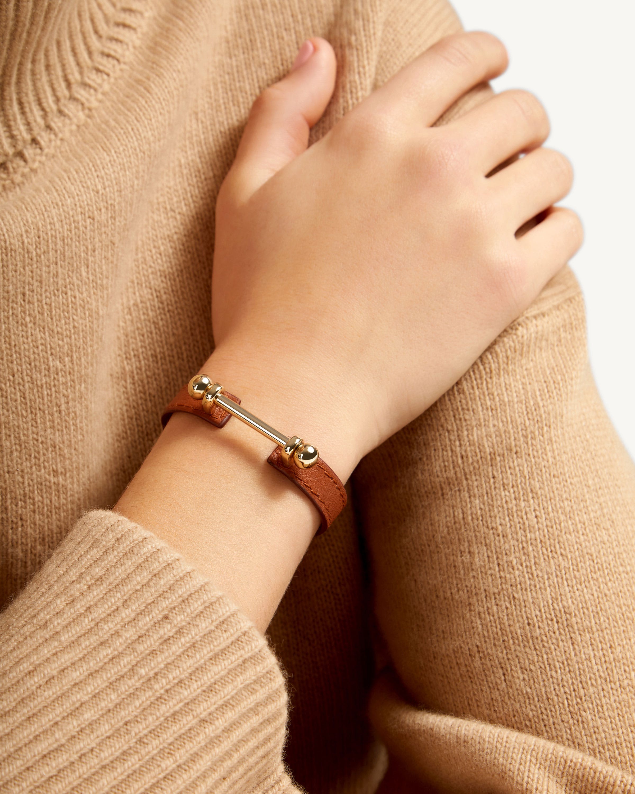 A woman wearing a brown sweater and a brown bracelet