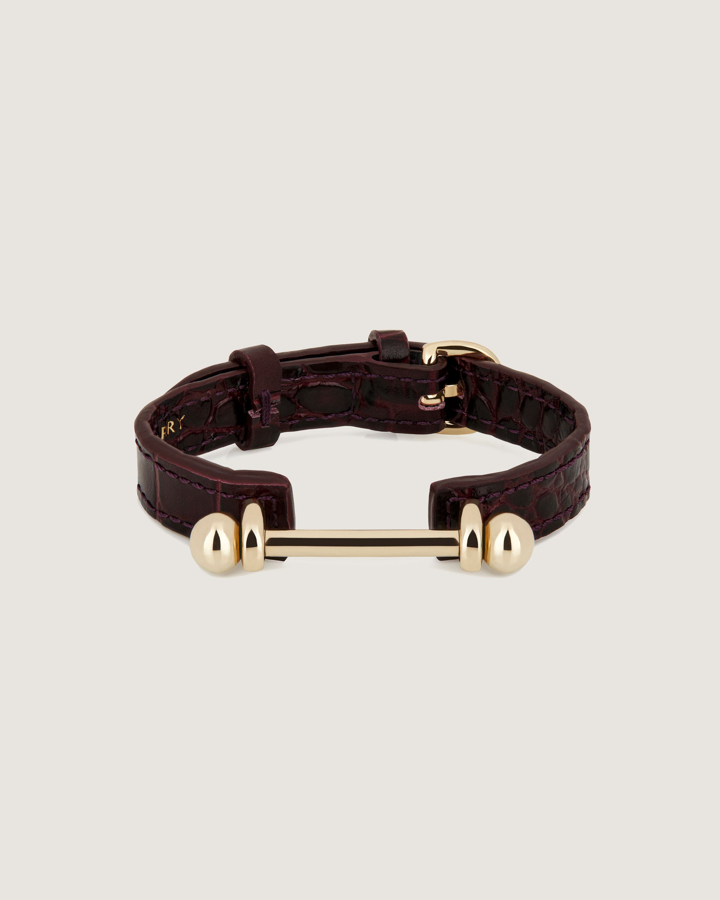 A brown leather bracelet with two gold balls