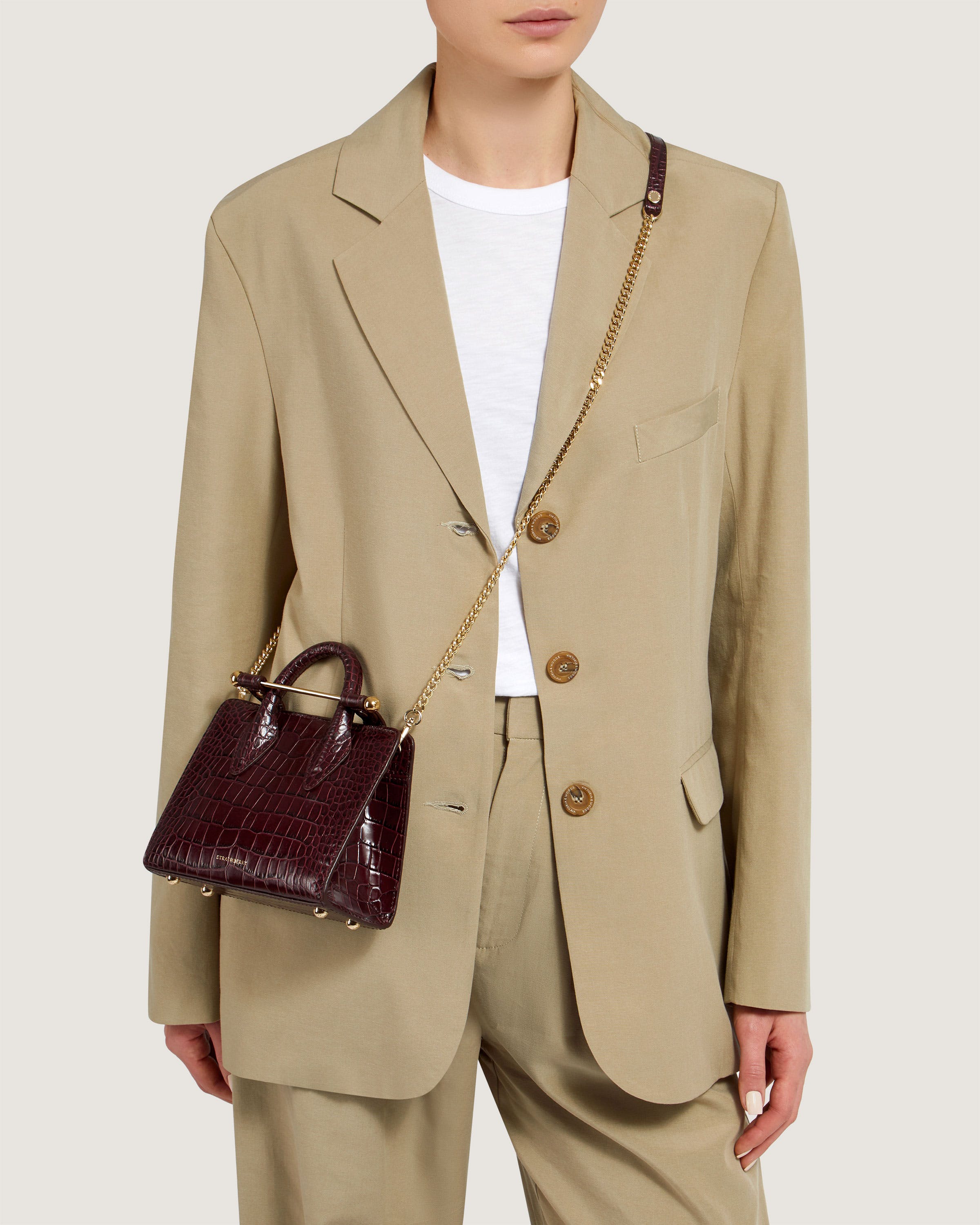 A woman wearing a tan suit and holding a brown purse