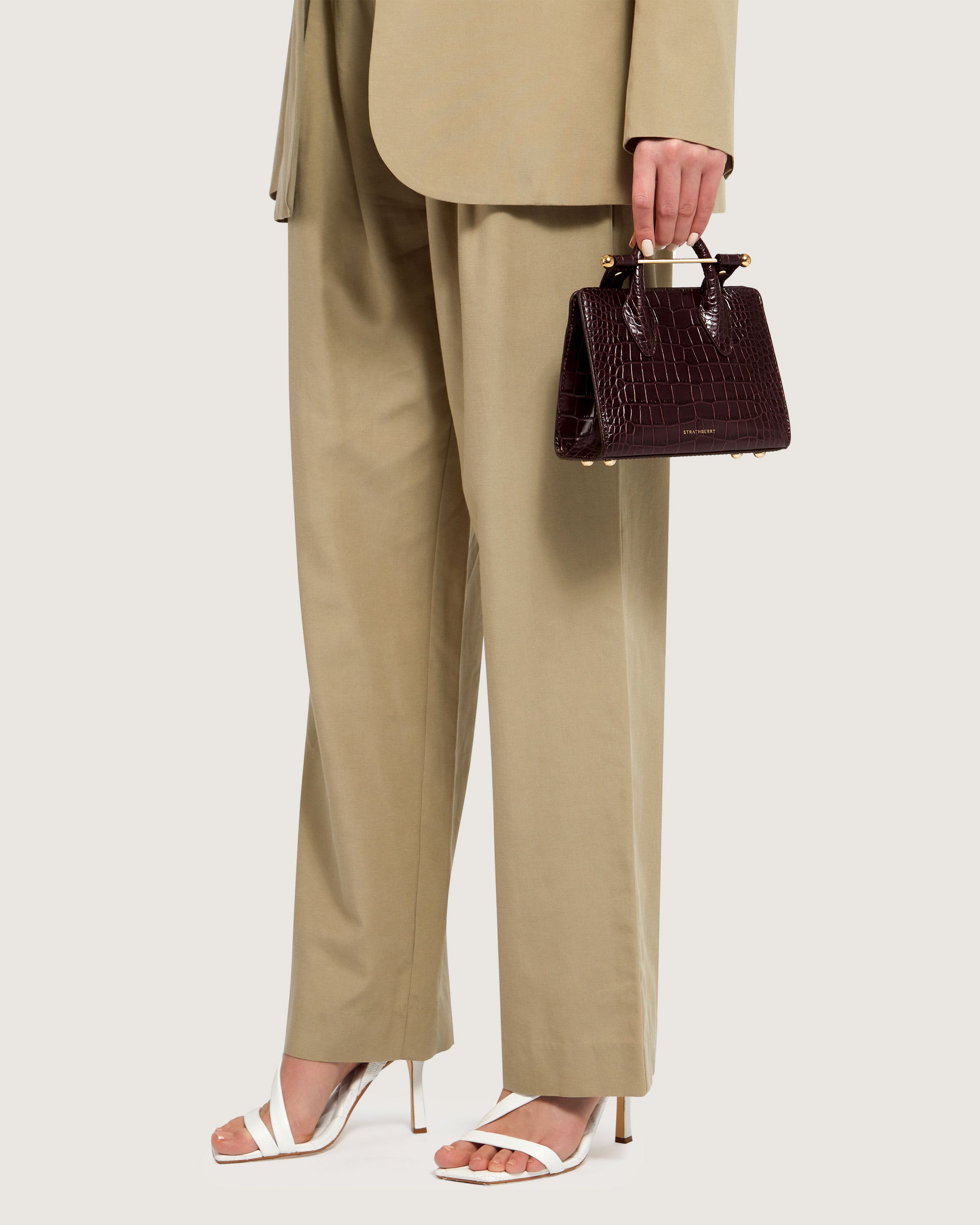 A woman in a tan suit holding a brown purse