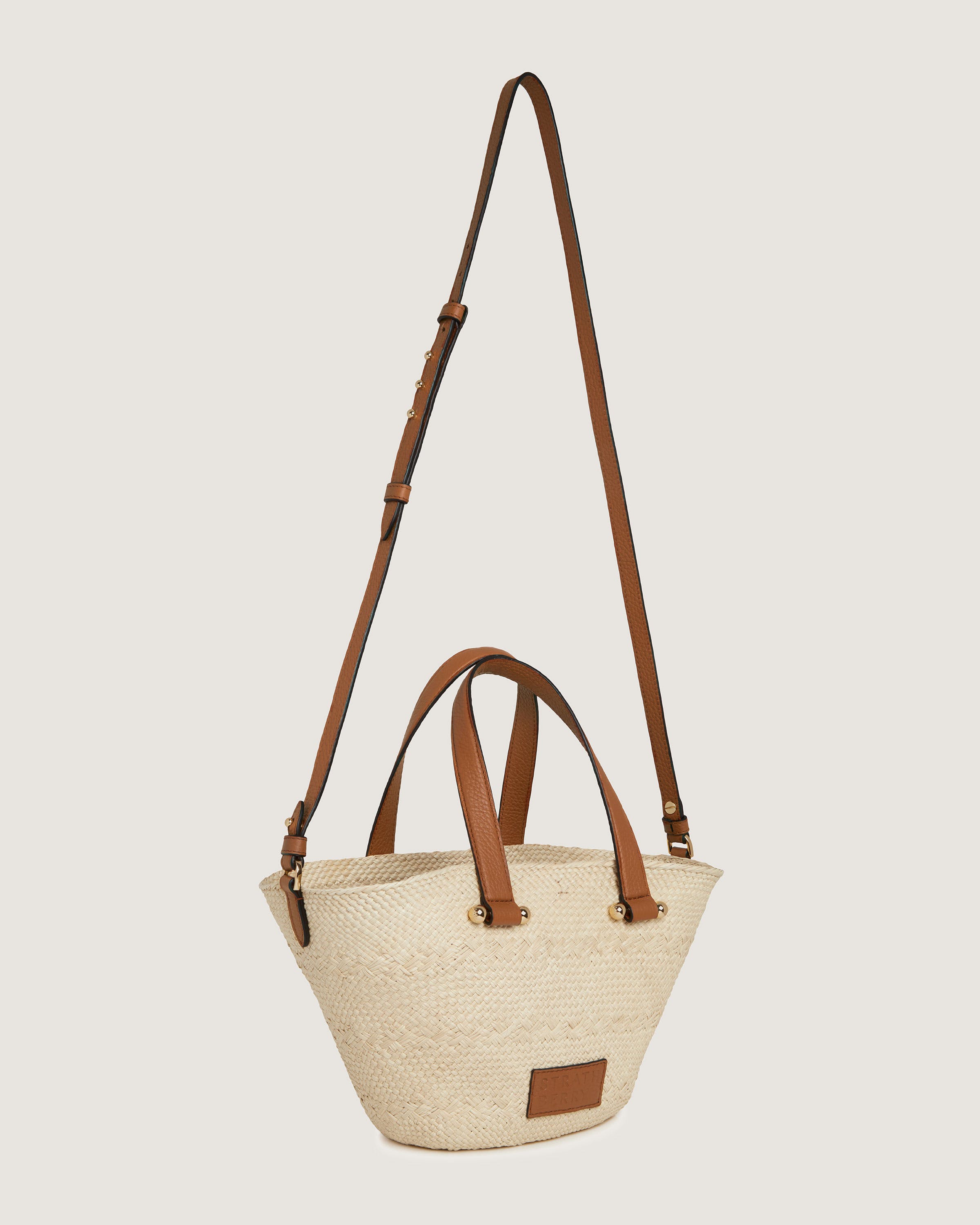 A white bag with brown straps hanging from it