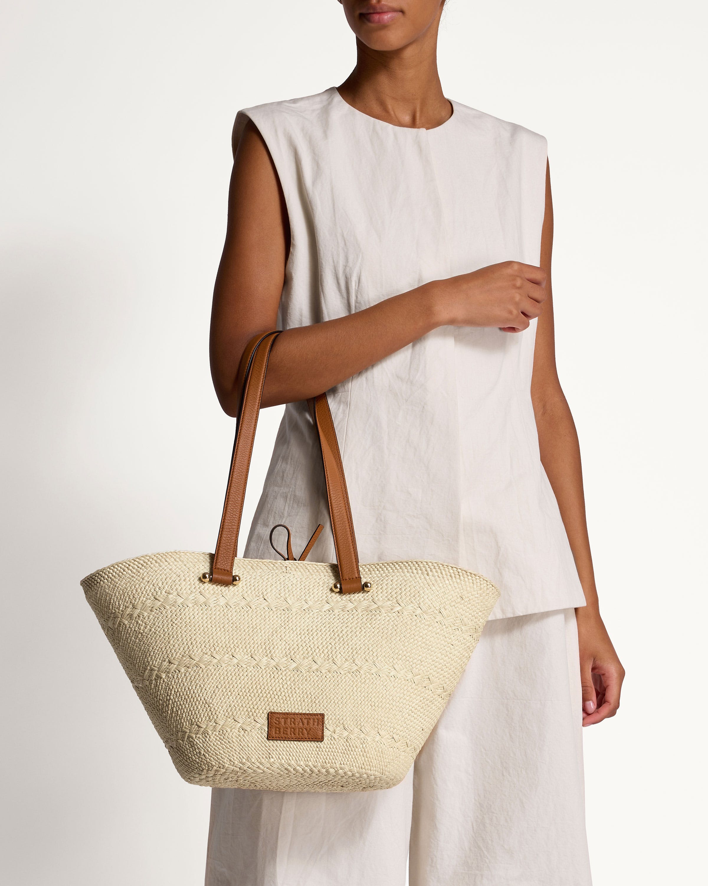 A woman holding a white bag with a brown handle