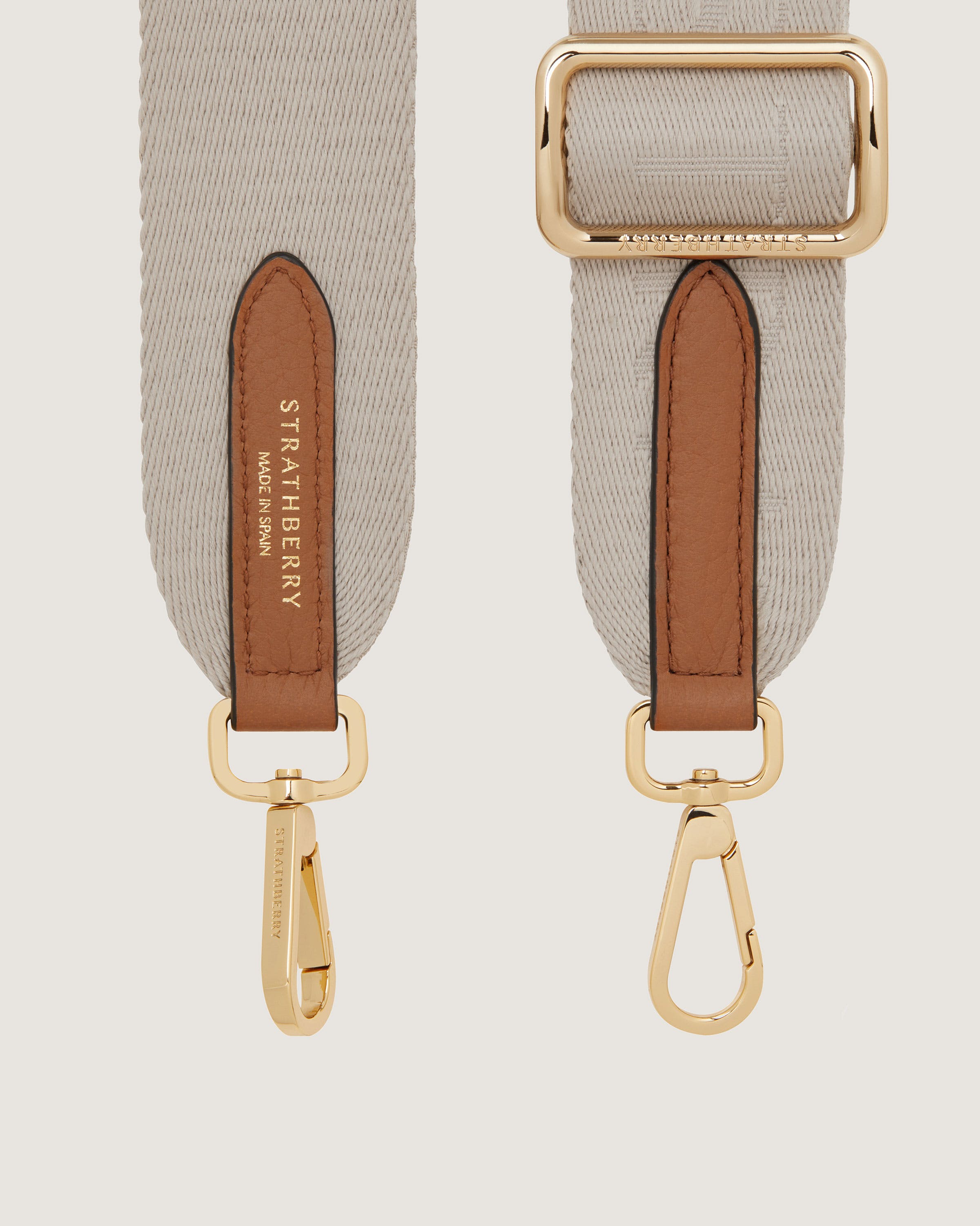 A pair of beige straps with a gold buckle