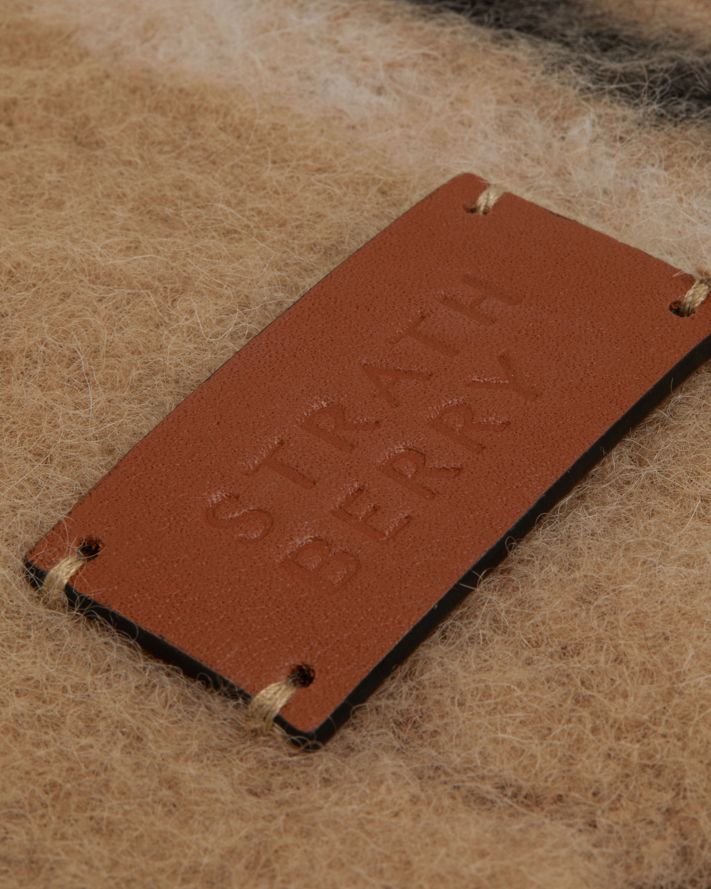 A brown leather case sitting on top of a pile of wool