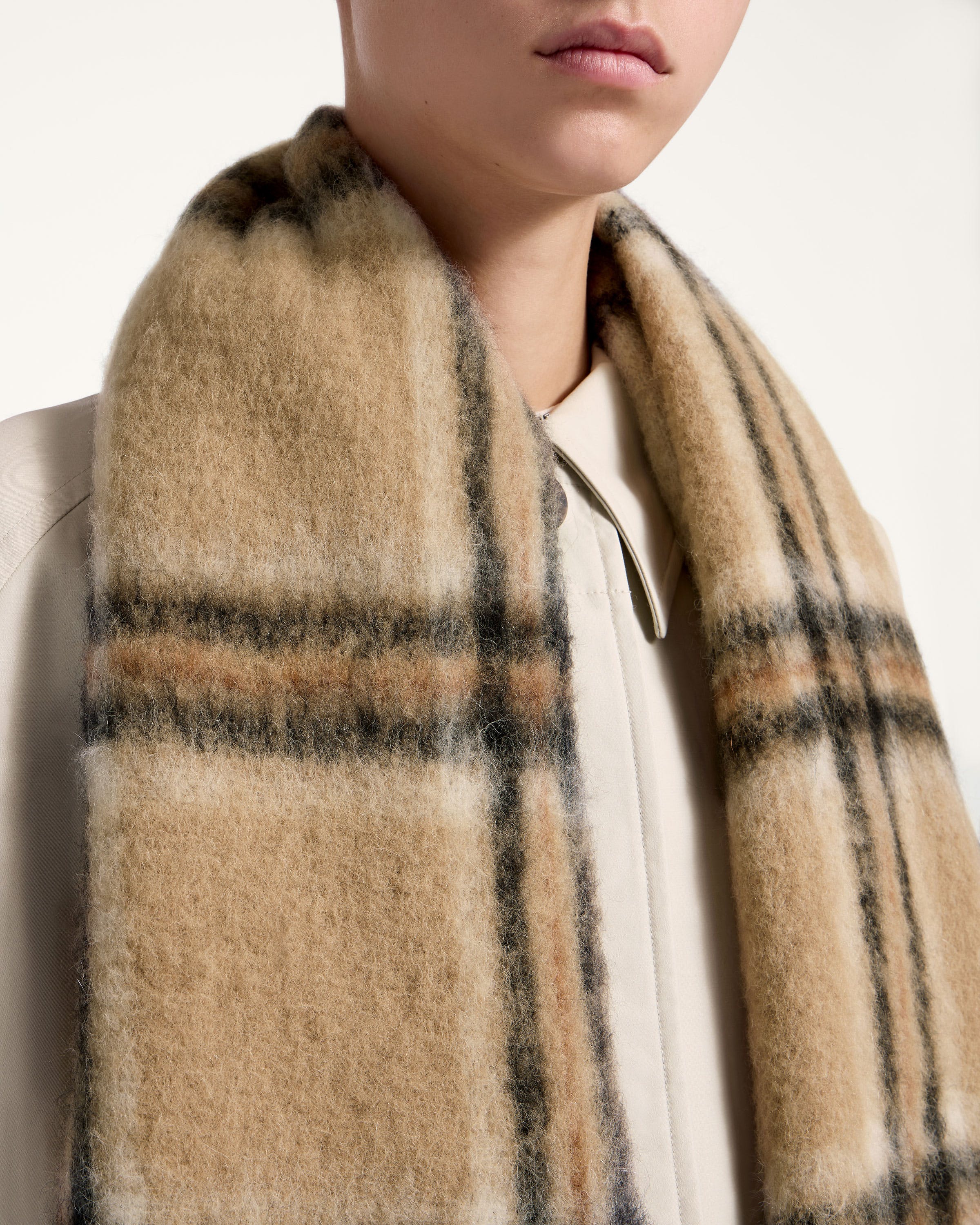 A woman wearing a tan and black plaid scarf