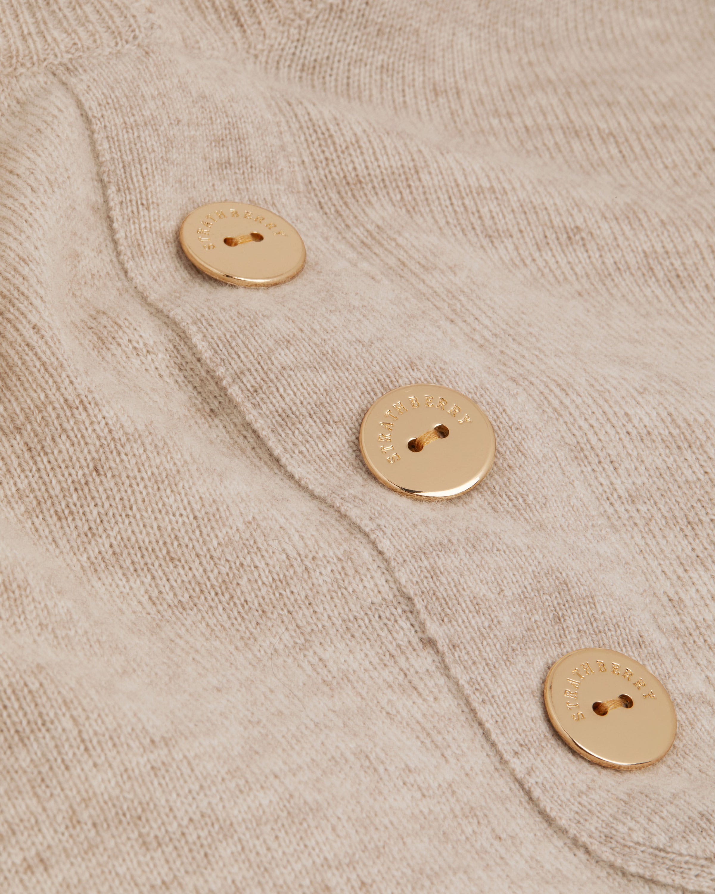 A pair of buttons on a beige sweater