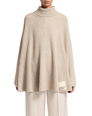 Una donna che indossa un maglione beige e pantaloni bianchi