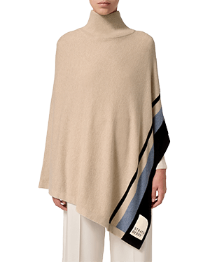 Una donna che indossa un poncho beige con una striscia nera