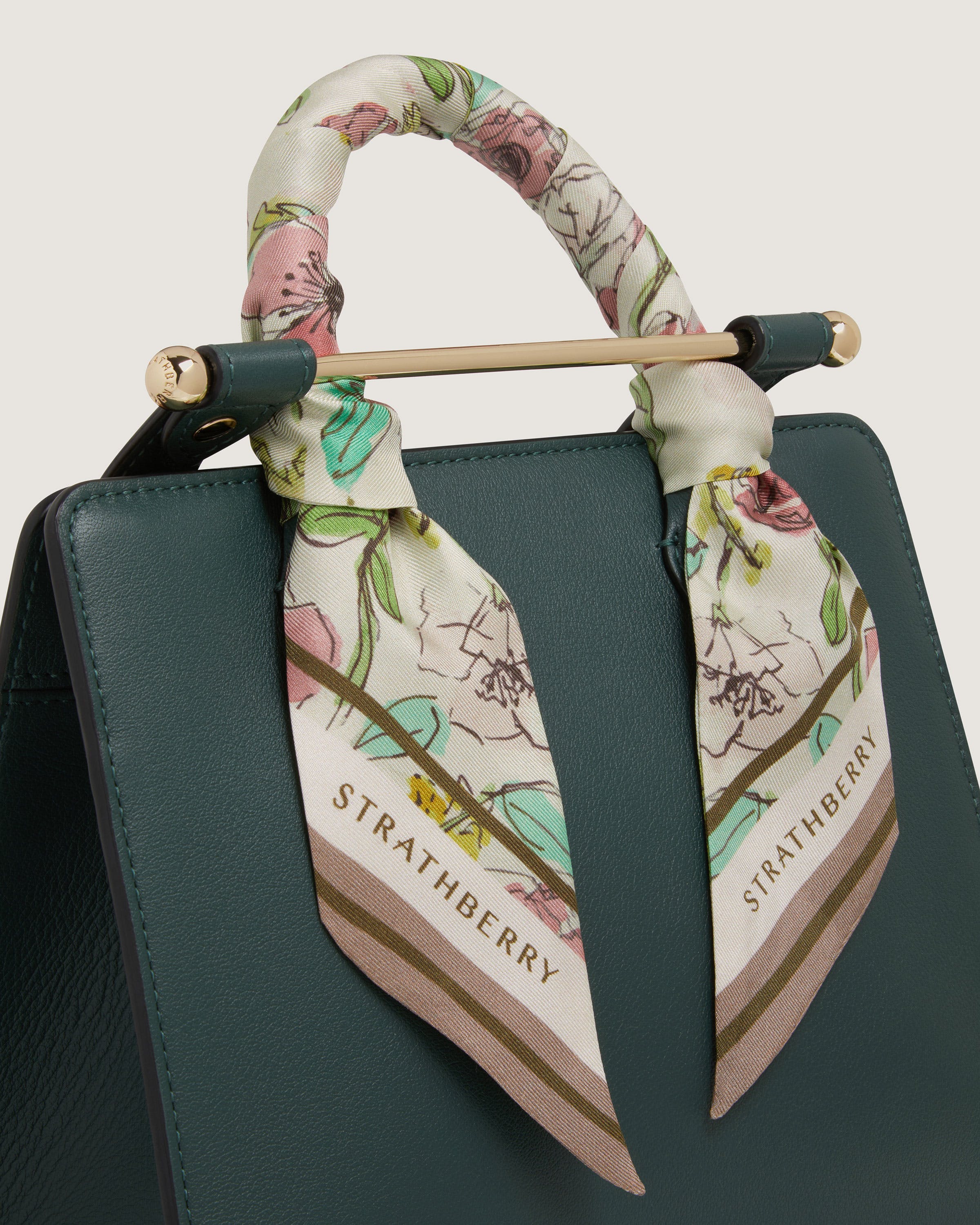 A green handbag with a floral scarf on it