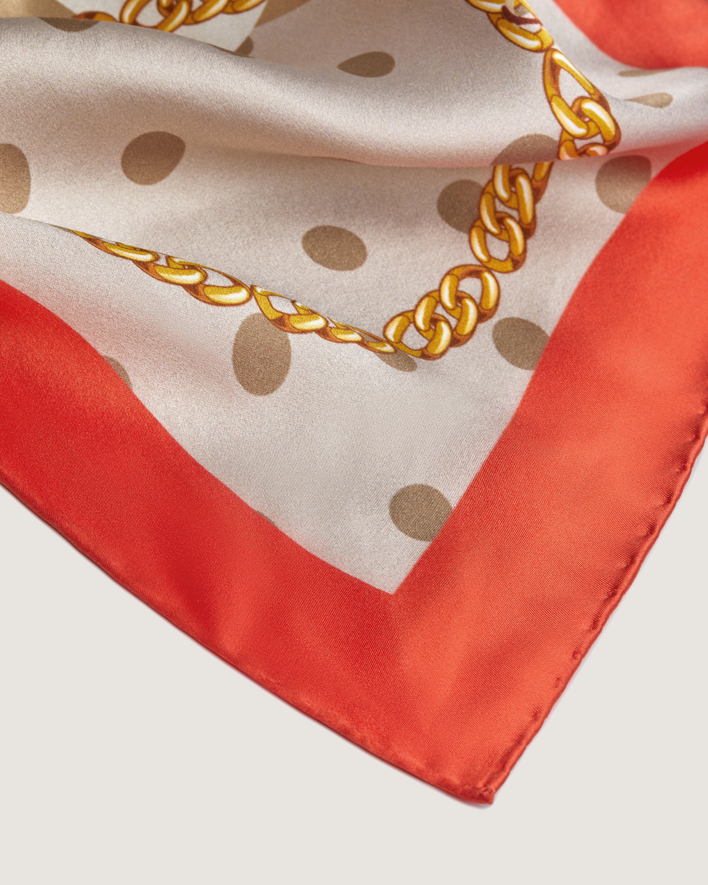 A red and white scarf with a gold chain on it