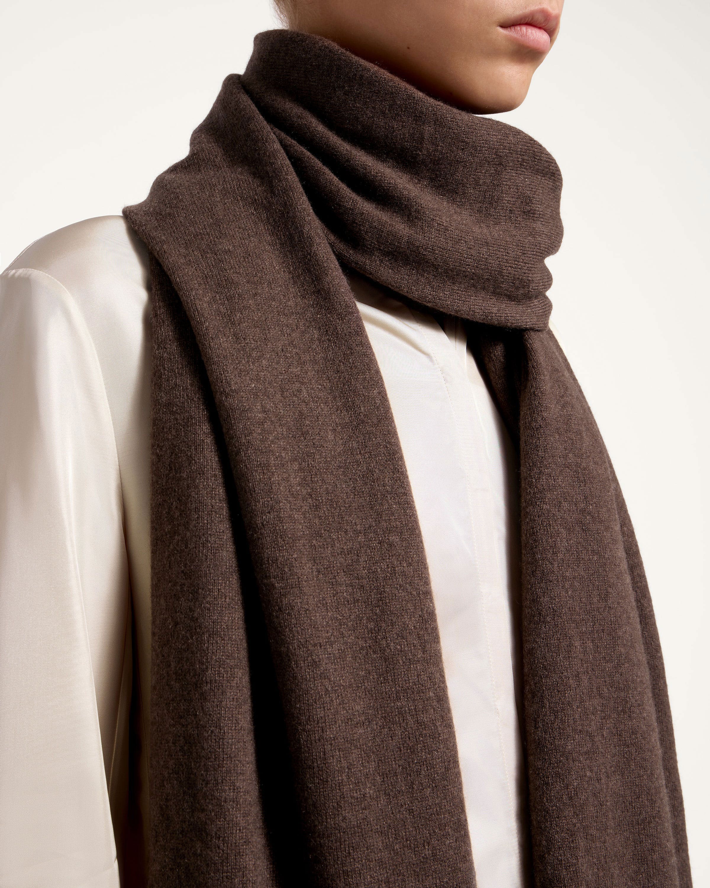 A woman wearing a brown scarf and a white shirt