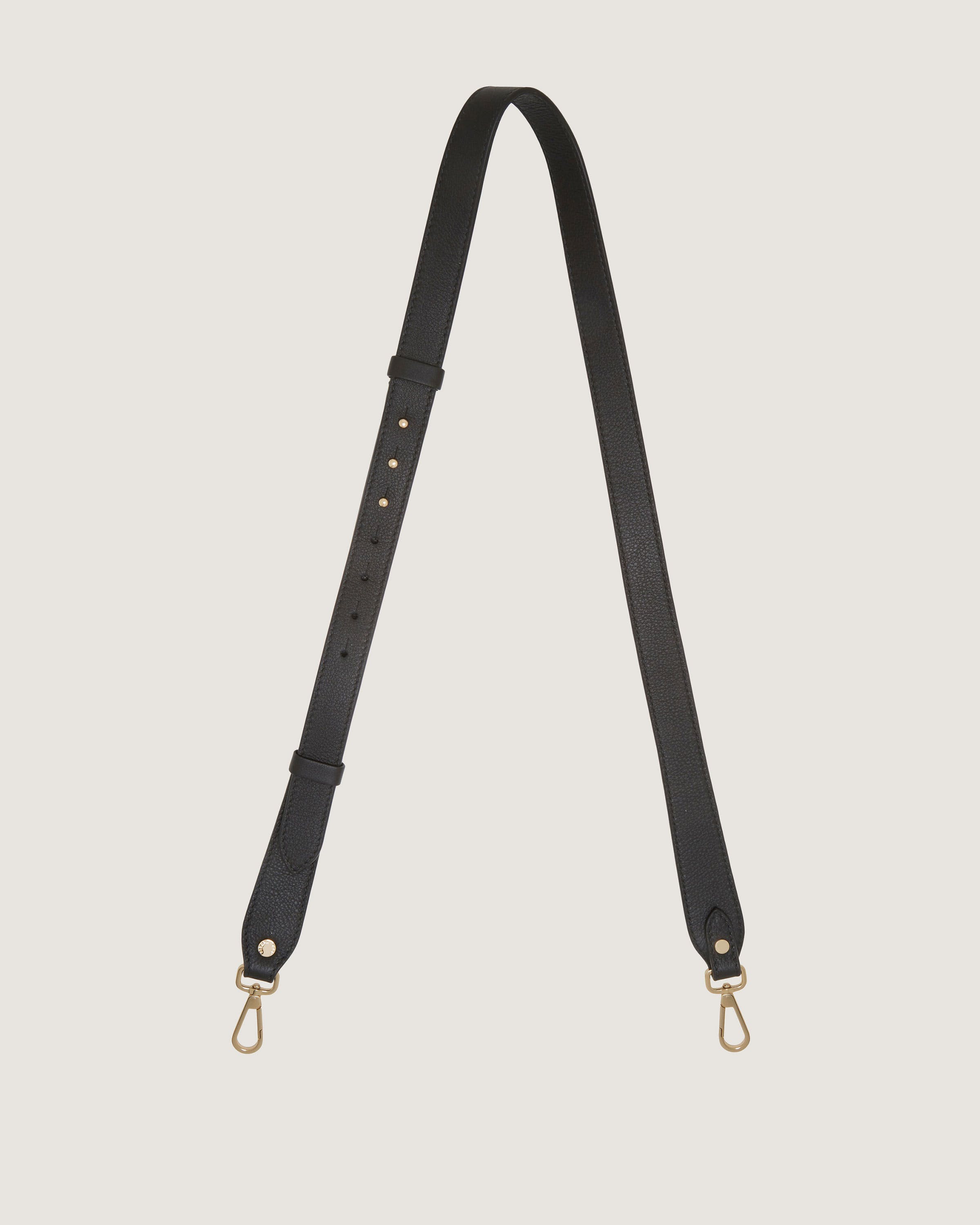 A black leather shoulder strap with gold hardware