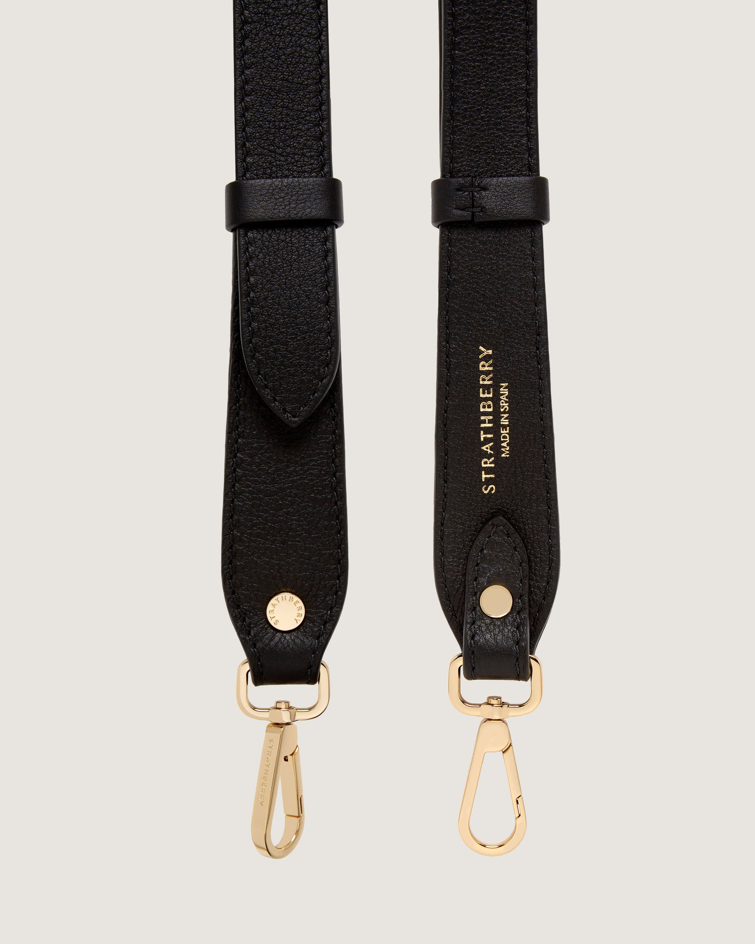 A pair of black leather straps with gold hardware