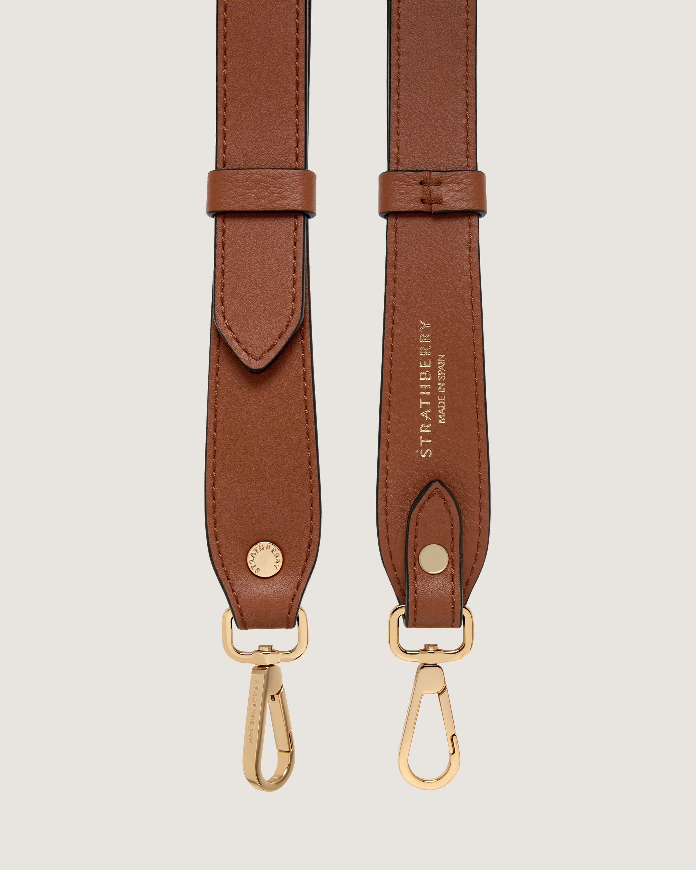 A pair of brown leather straps with gold hardware