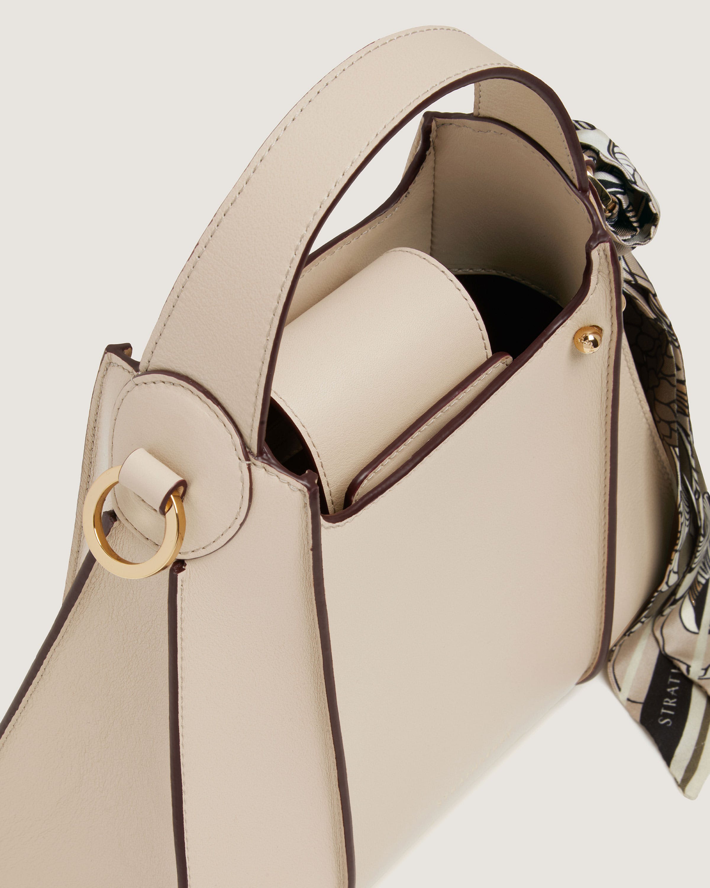 A white purse with a gold ring on the handle