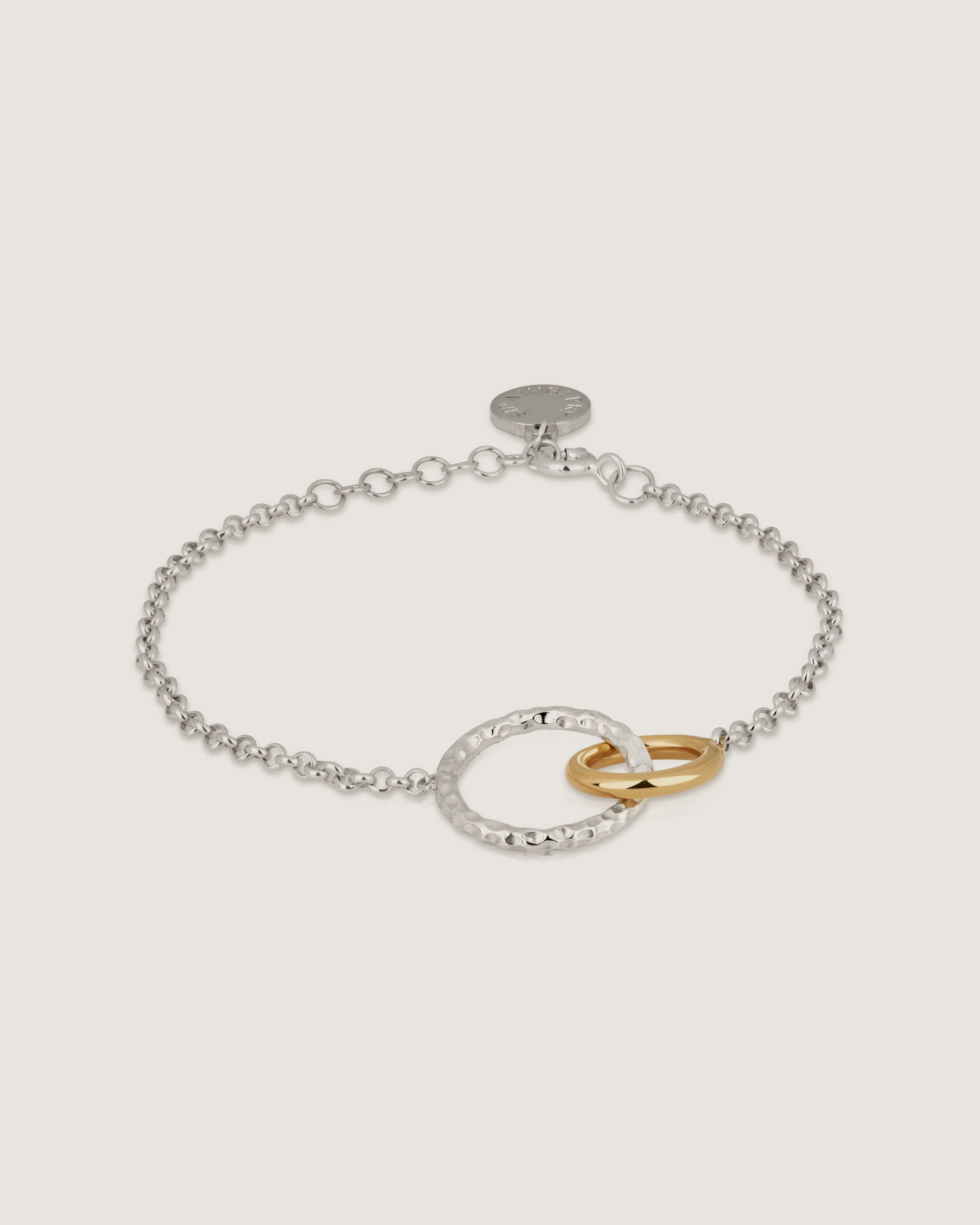 A silver and gold bracelet with a circle clasp