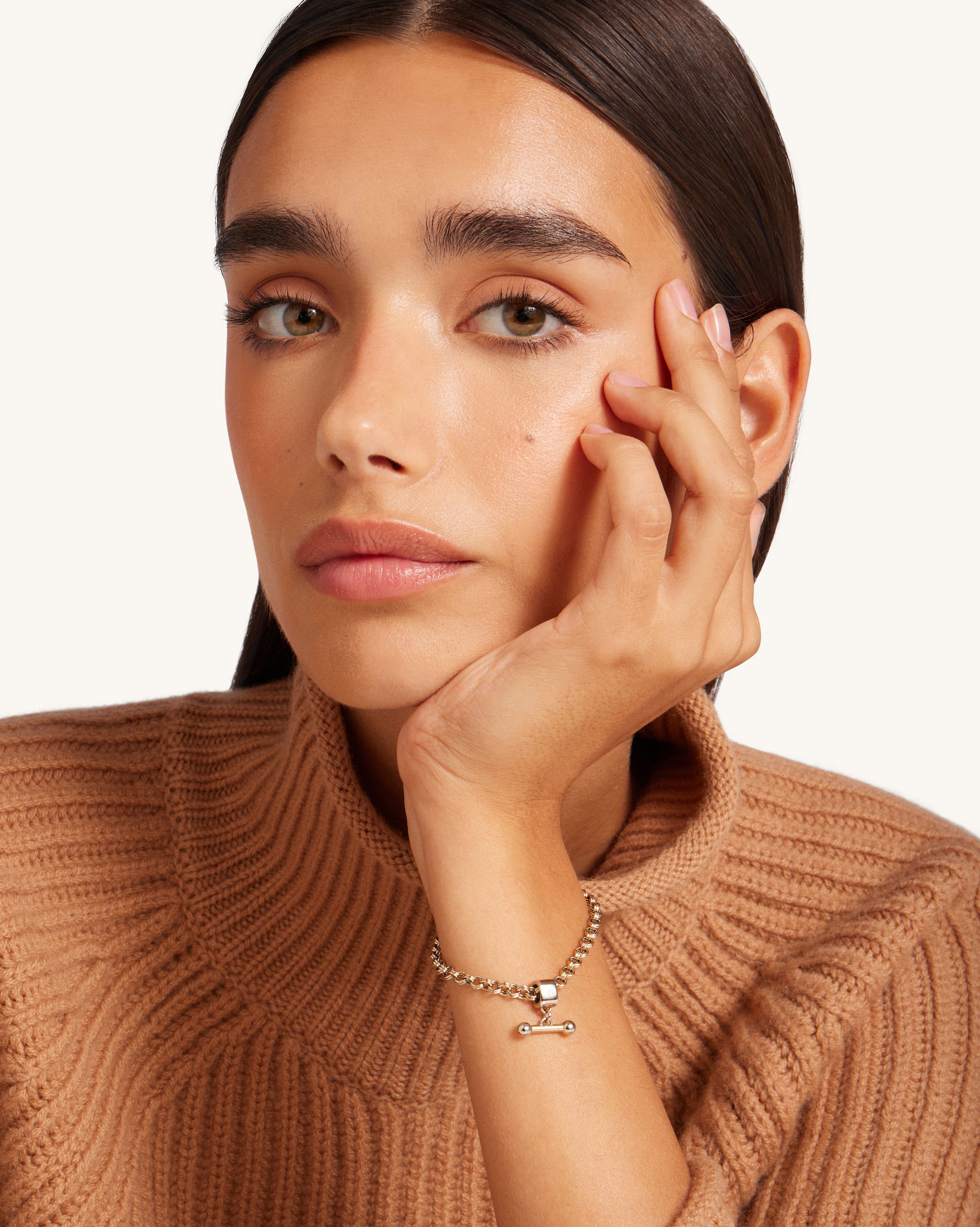 A woman wearing a brown sweater and a gold bracelet