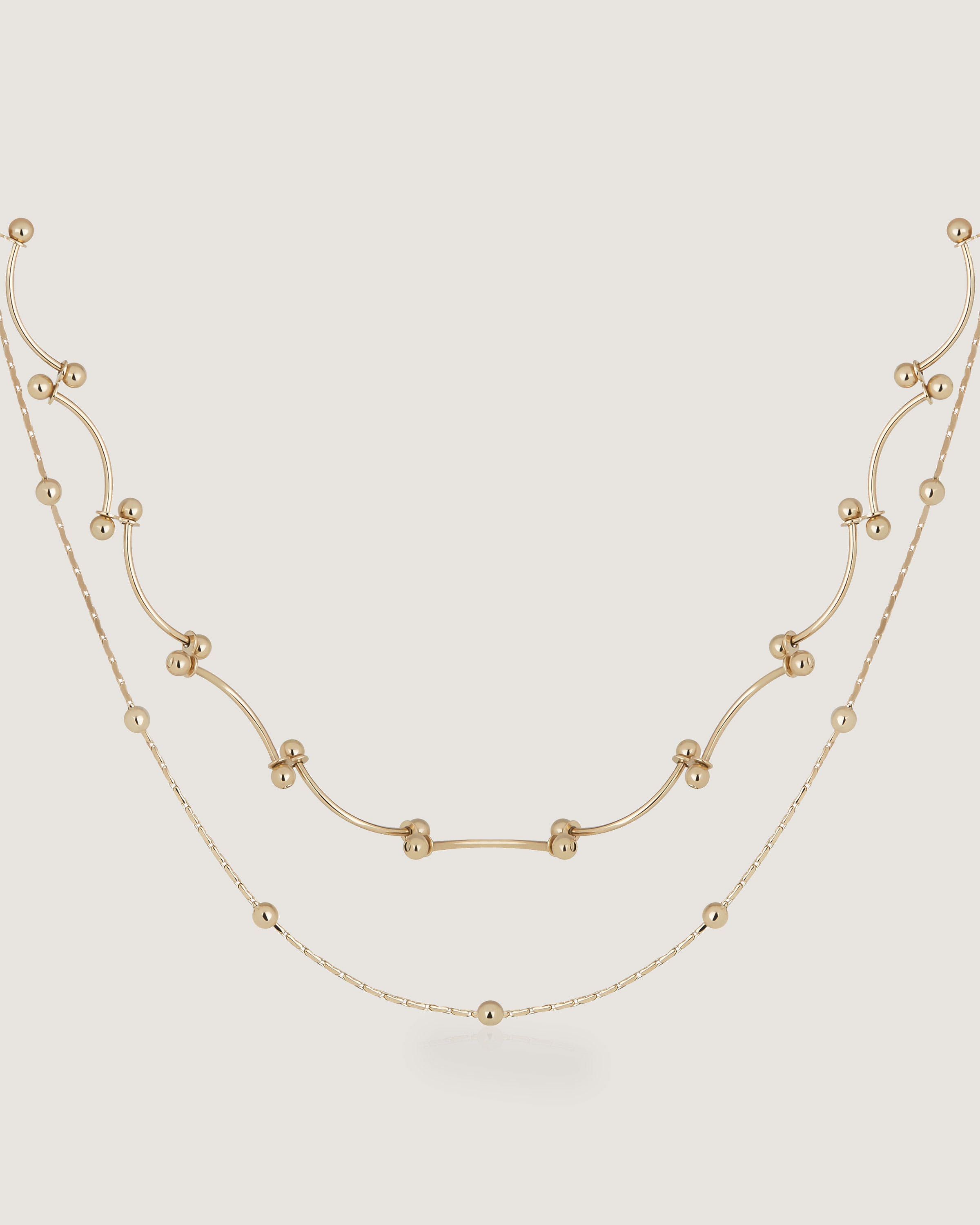 A gold necklace with beads on a white background