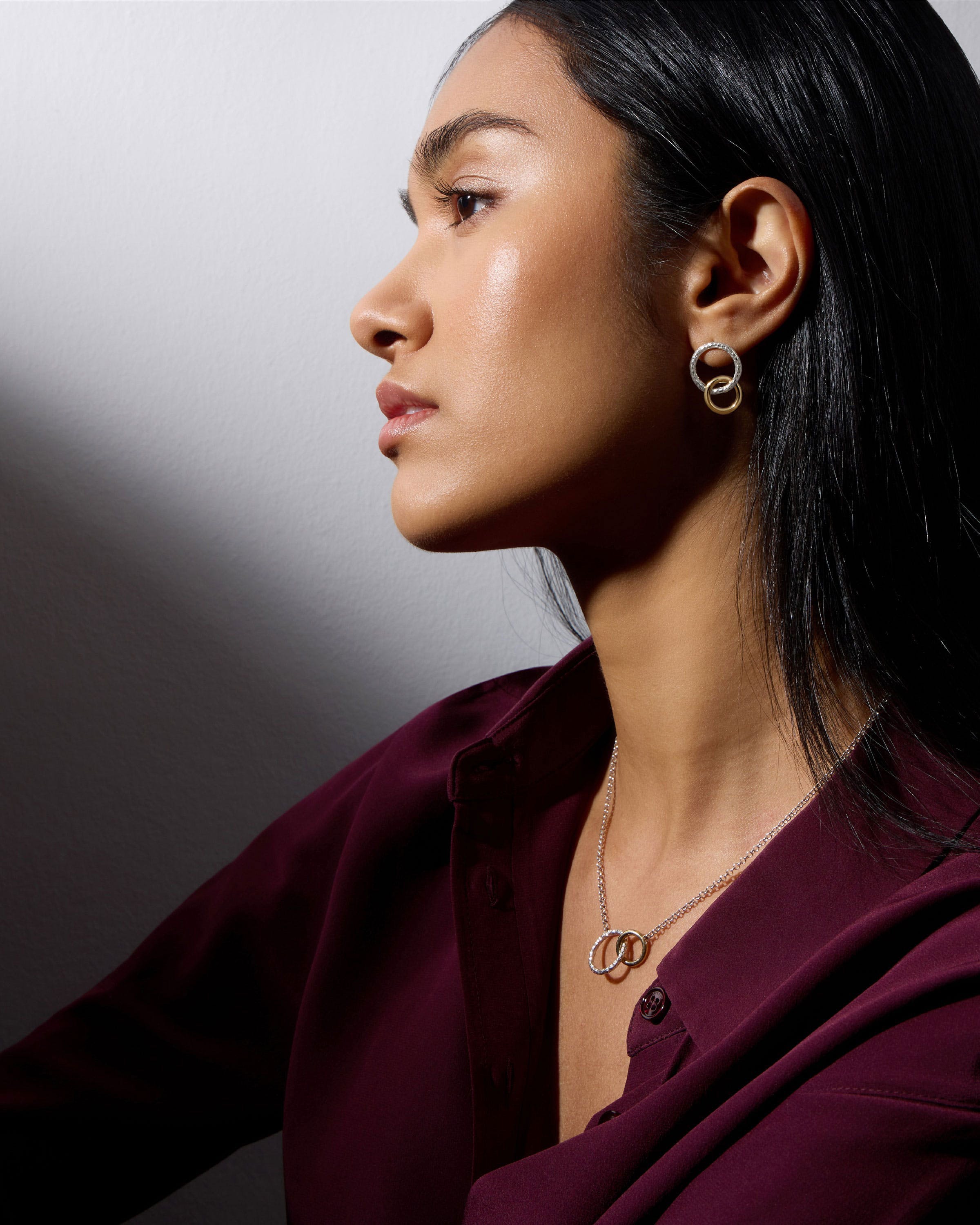 A woman in a purple shirt is wearing a pair of earrings