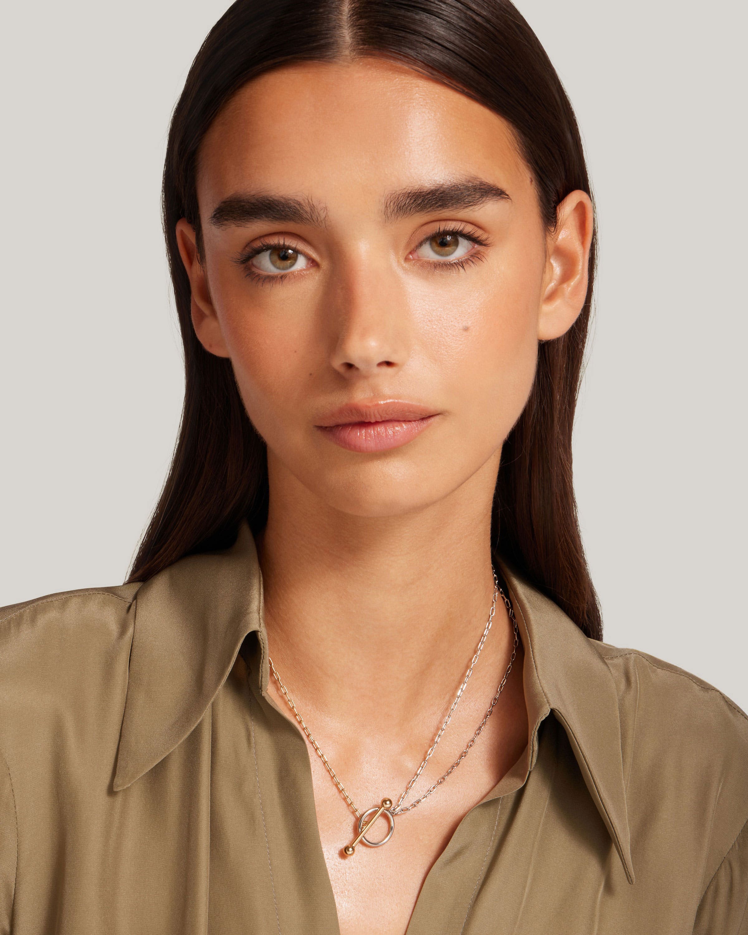 A woman wearing a tan shirt and a necklace