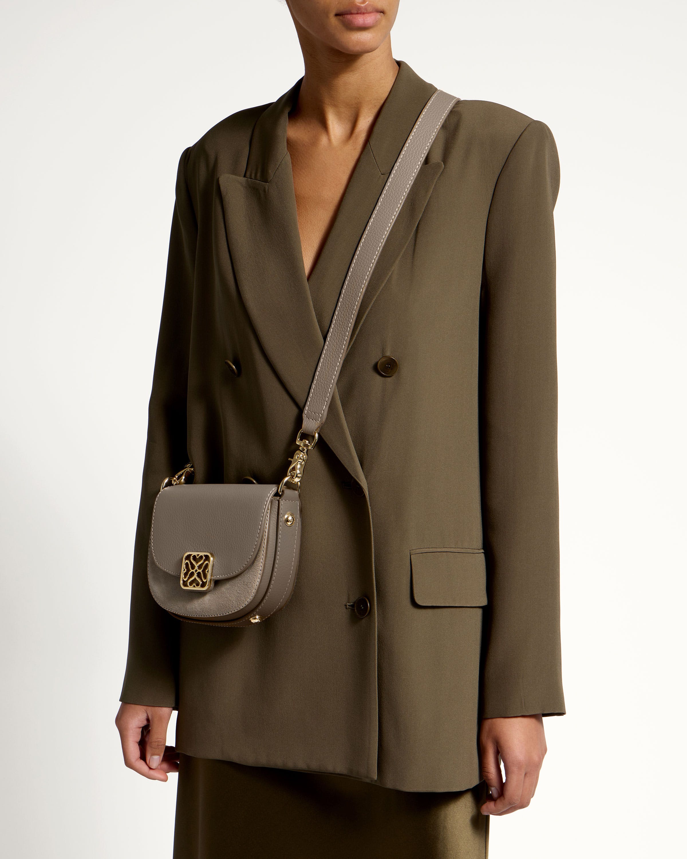 A woman in a green suit holding a gray purse