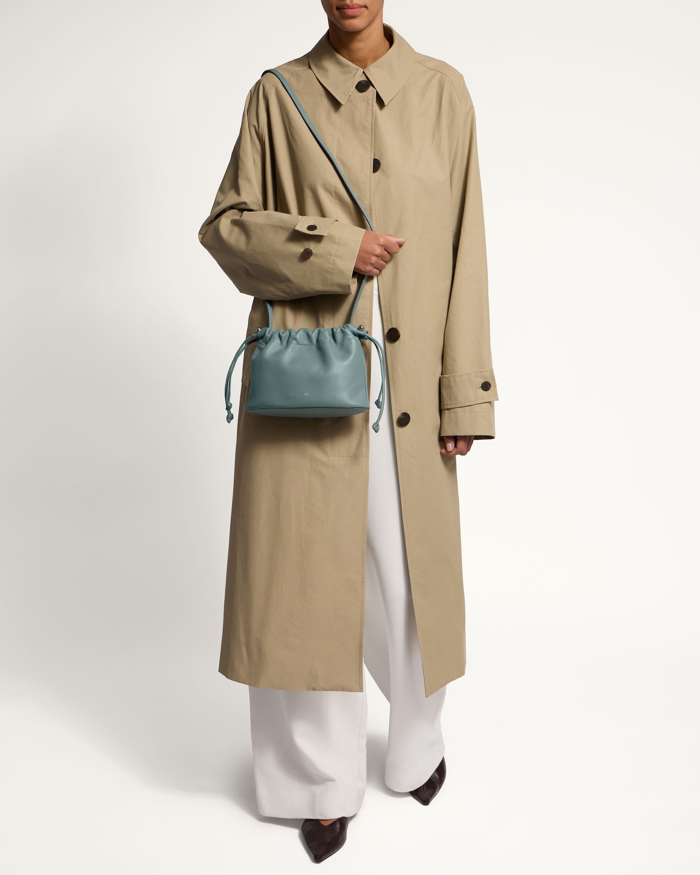 A woman wearing a trench coat and white pants