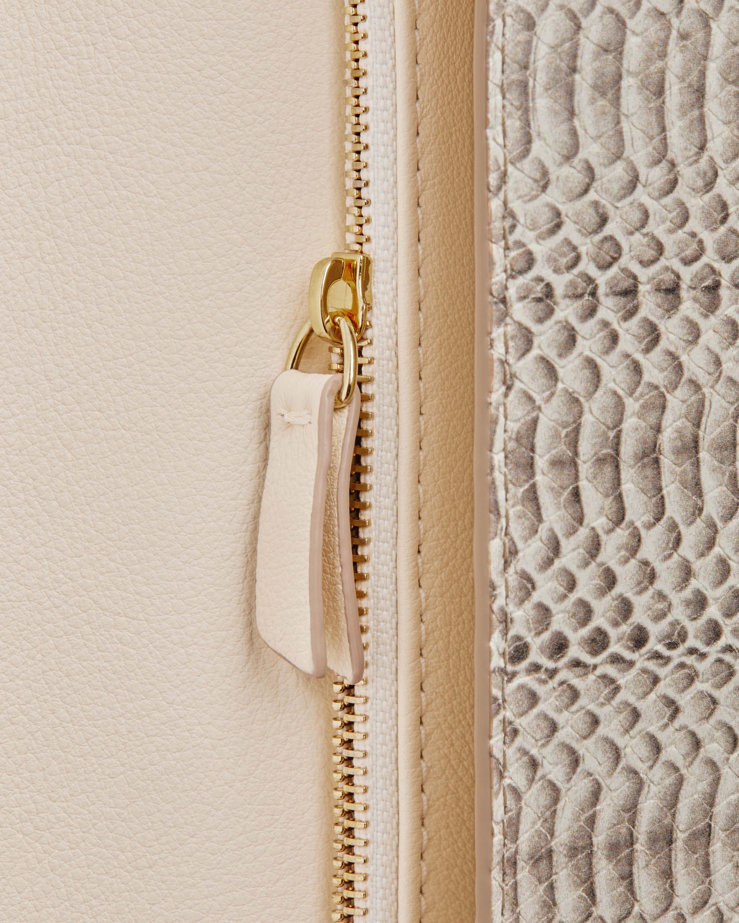 A close up of a zipper on a white purse