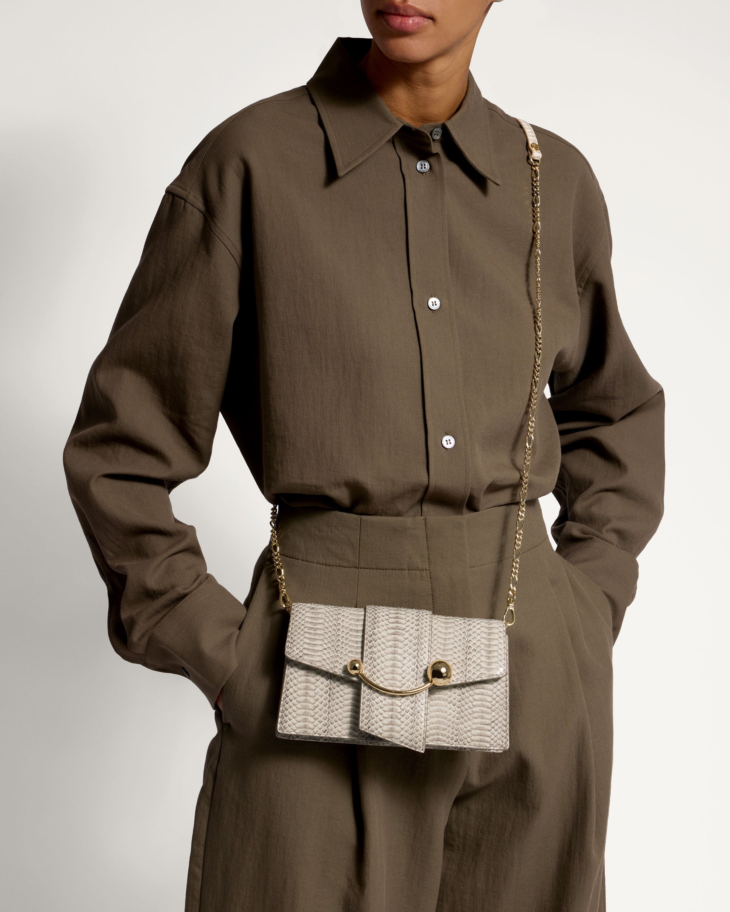 A woman wearing a brown shirt and a white purse