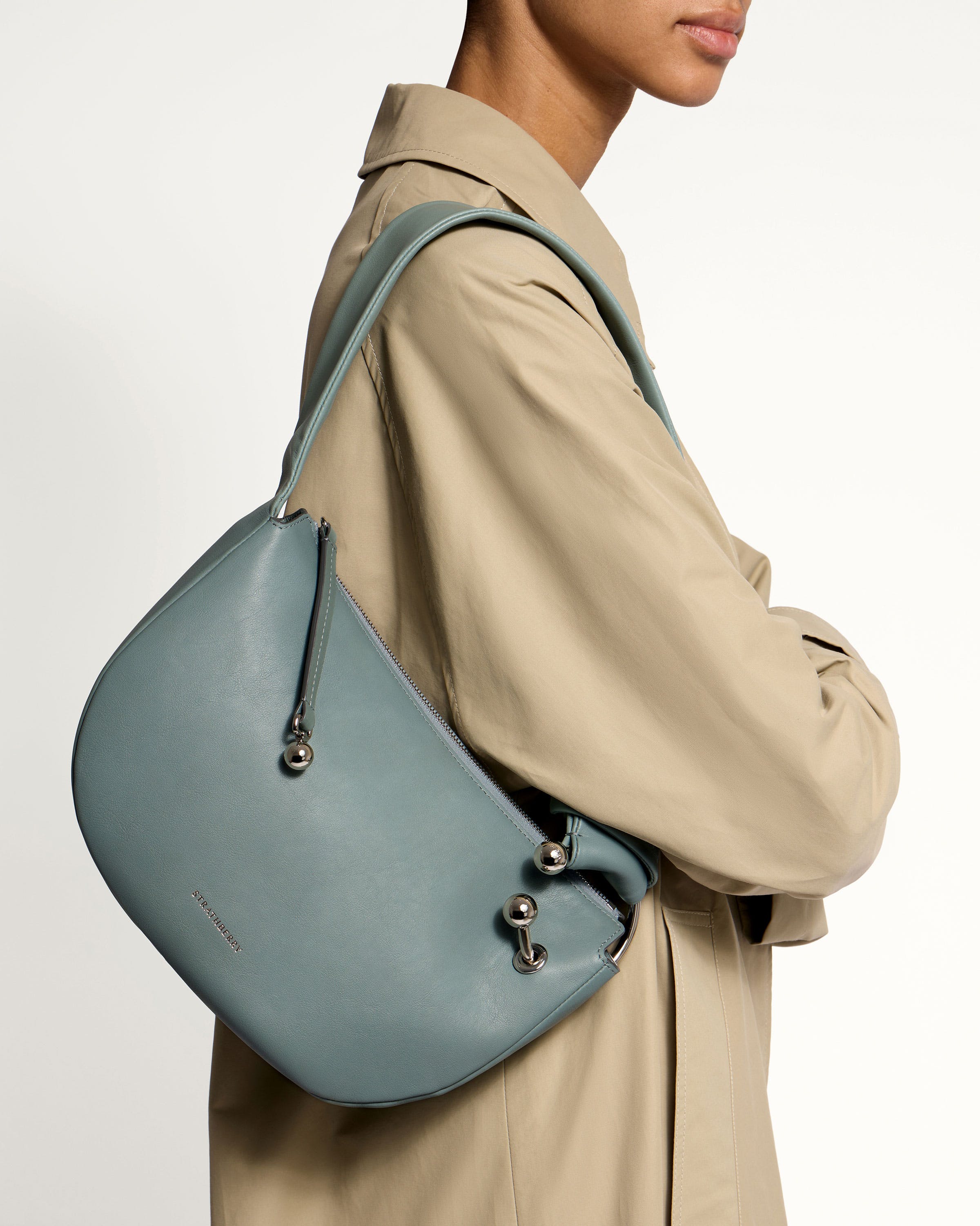 A woman in a trench coat holding a blue purse