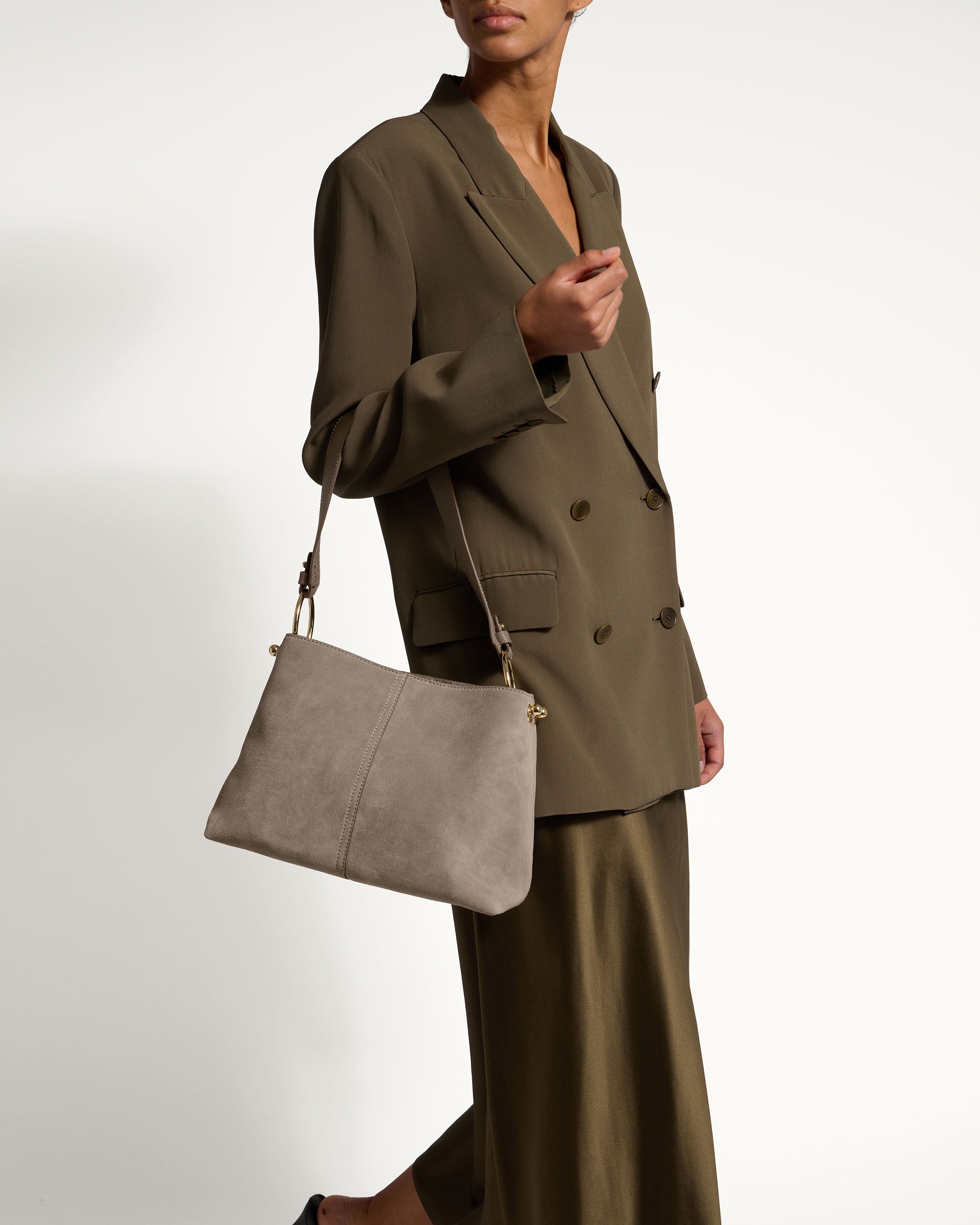 A woman in a brown suit carrying a gray purse